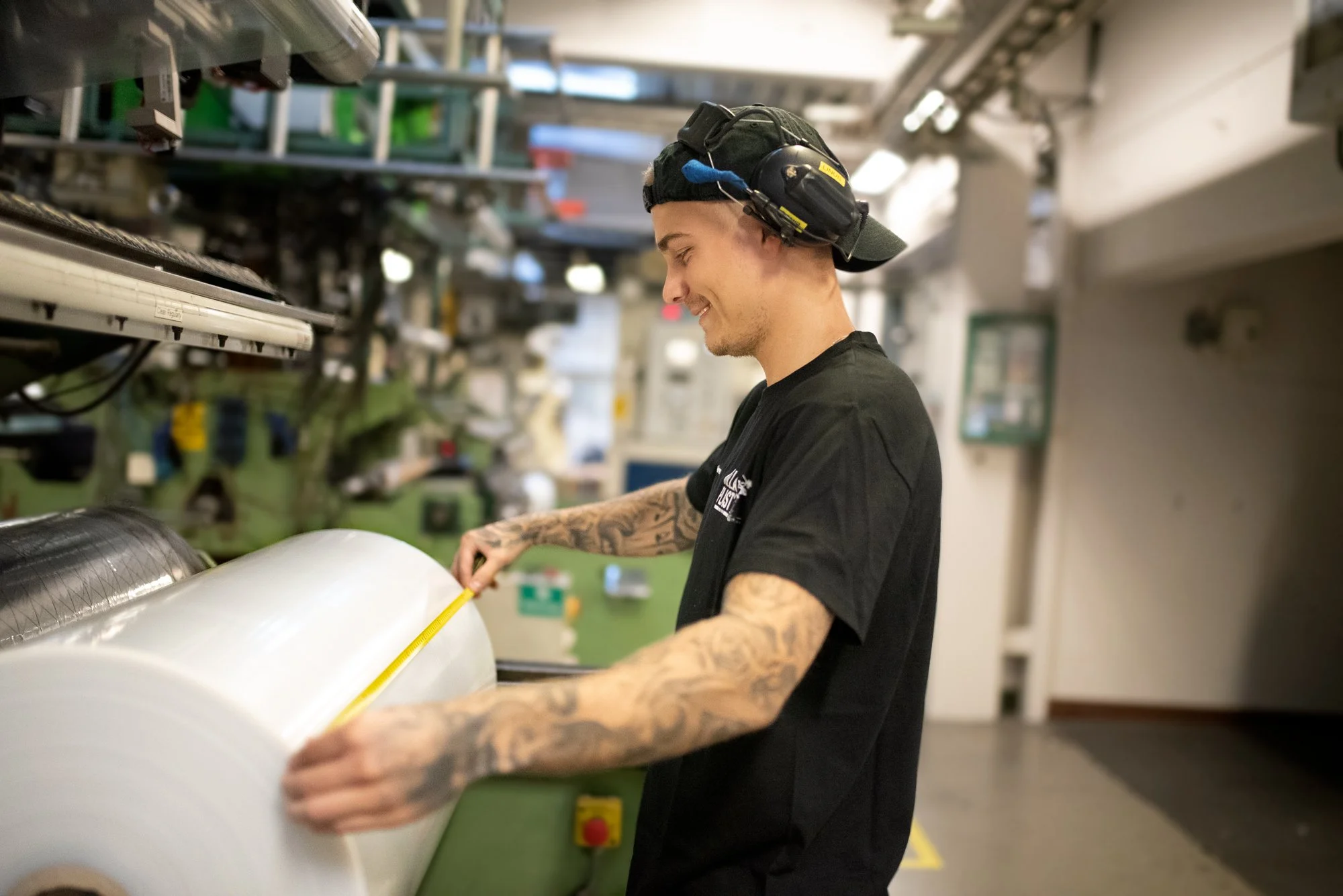 Maskinoperatör som mäter bredden på en rulle med plastfilm