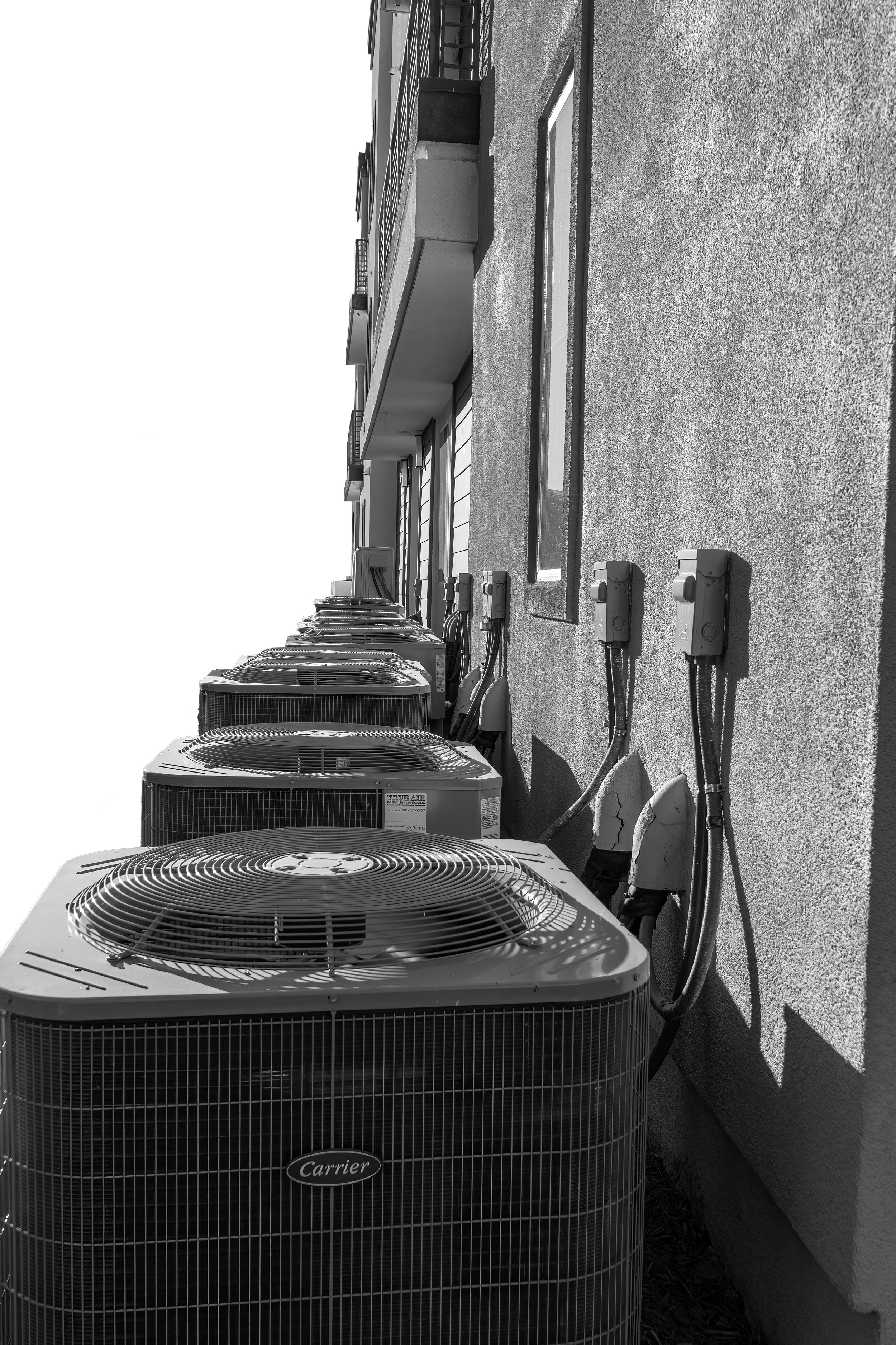 Six outdoor Carrier HVAC units installed on an apartment building