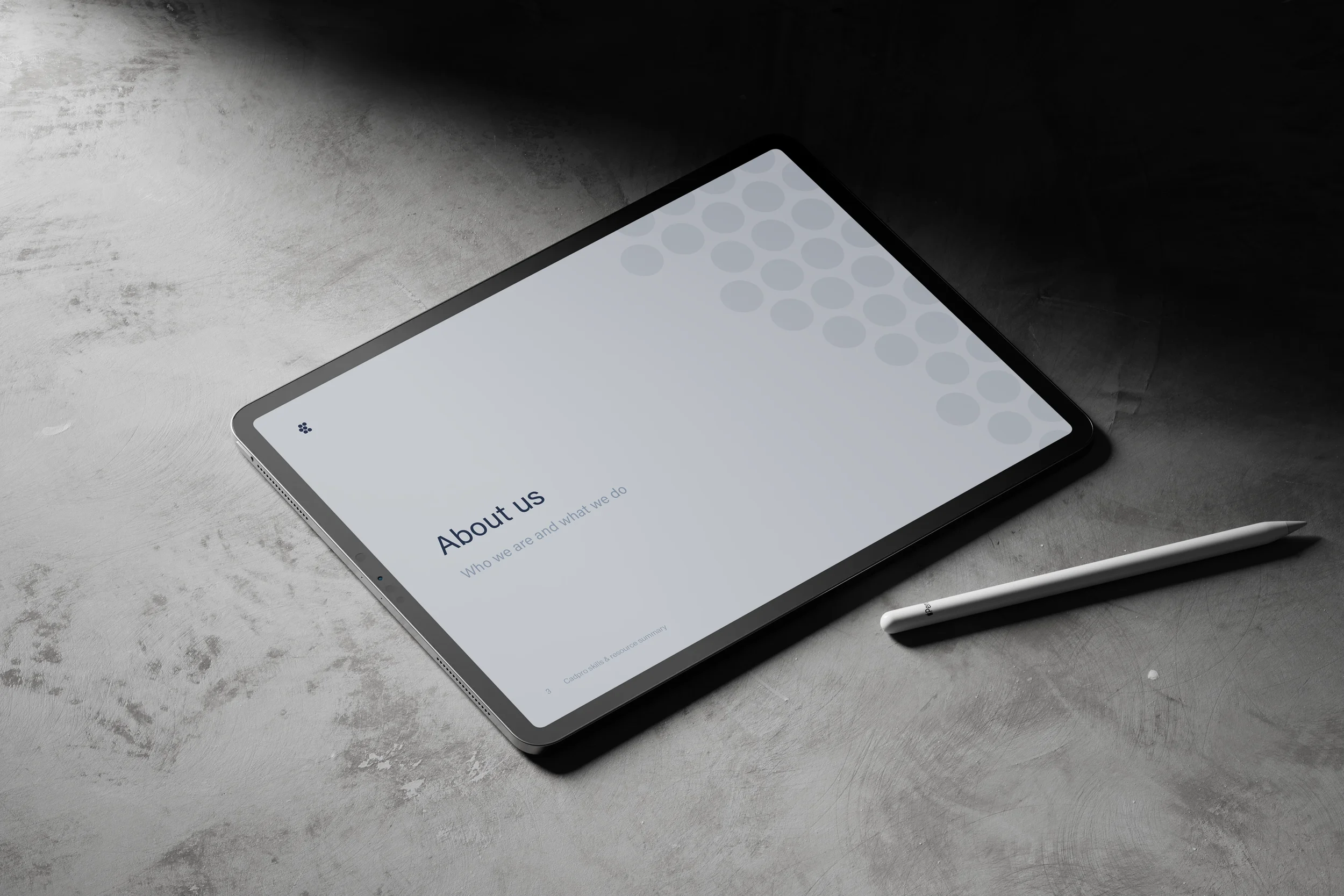 Tablet with a white screen displaying 'About us' section, resting on a gray surface with a stylus nearby.