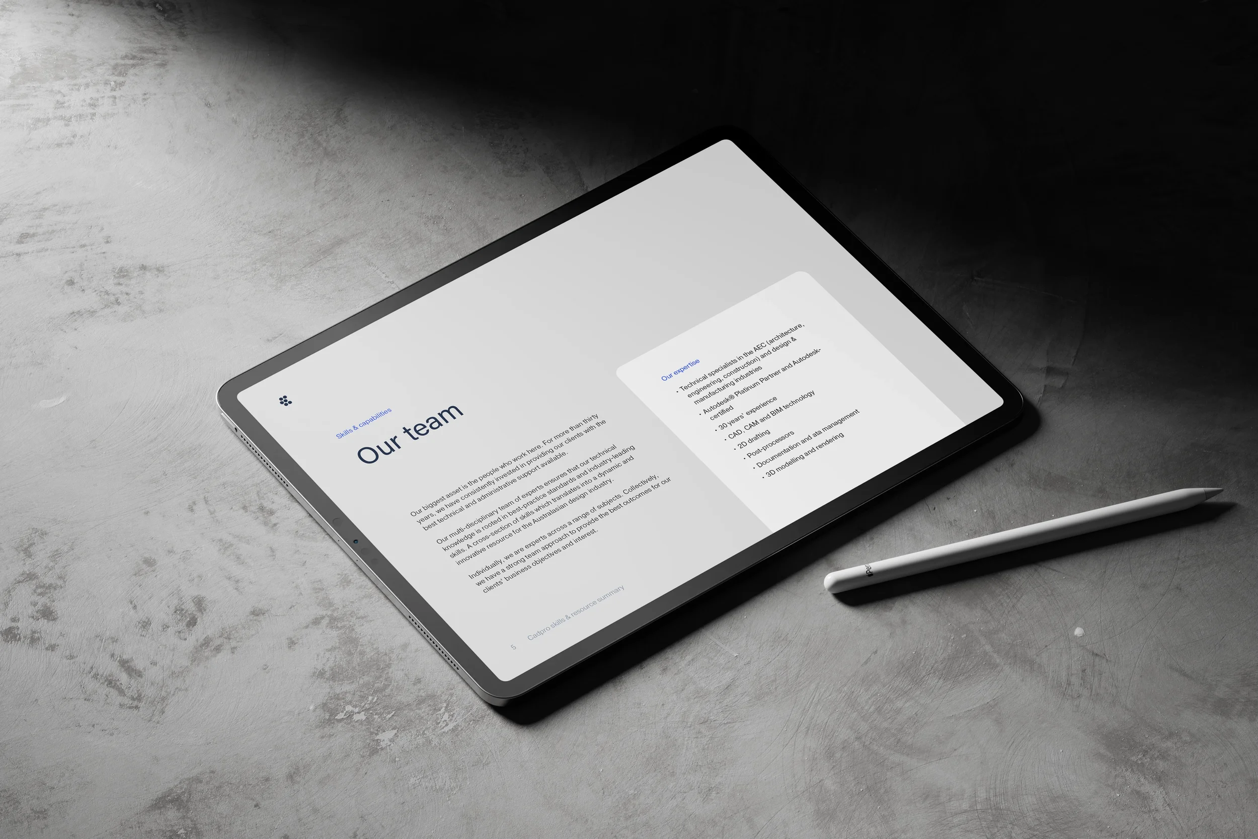 A tablet displaying a webpage titled 'Our team' resting on a gray textured surface, with a stylus placed beside it.