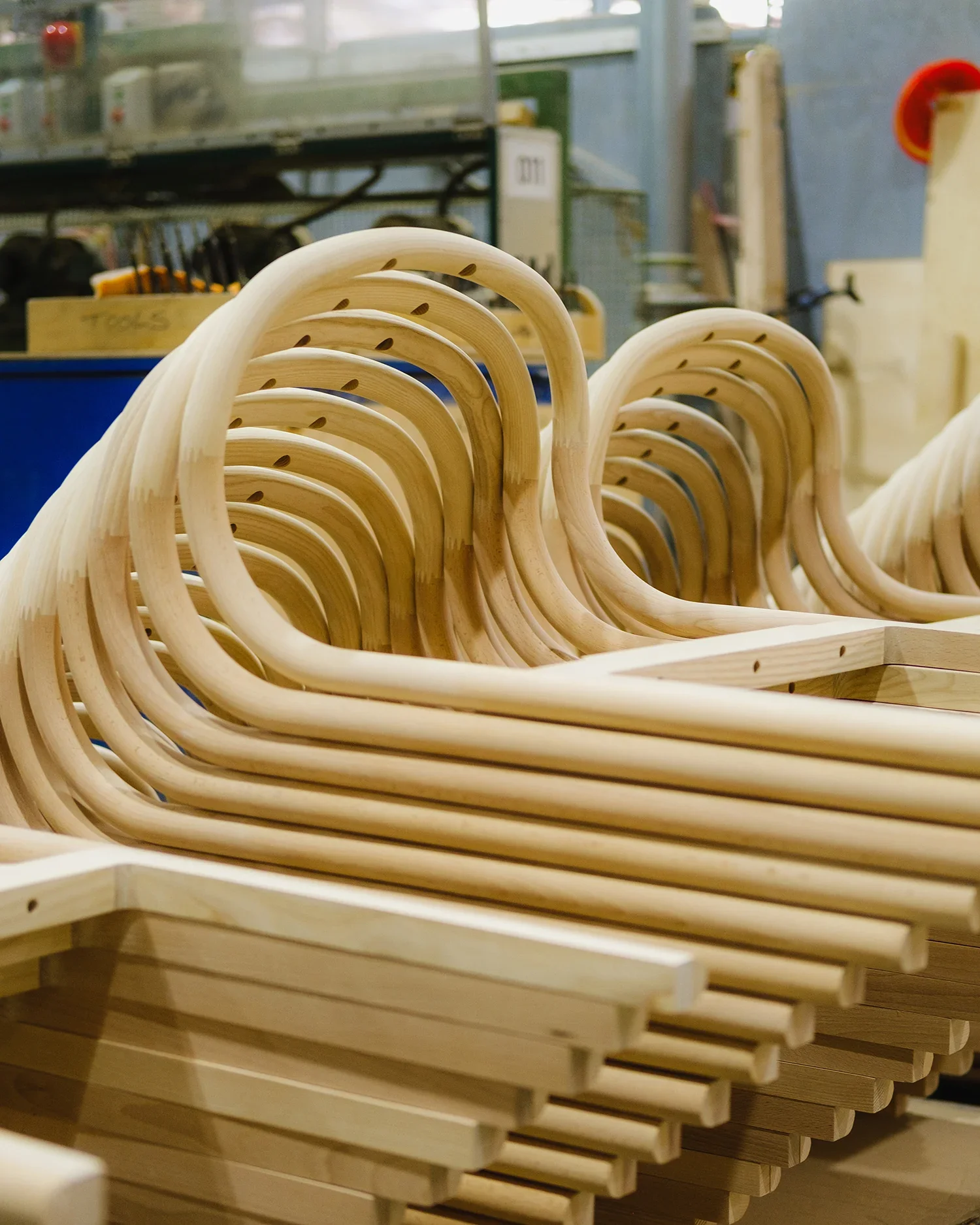 Row of wooden bent hangers stacked together in a woodworking shop.