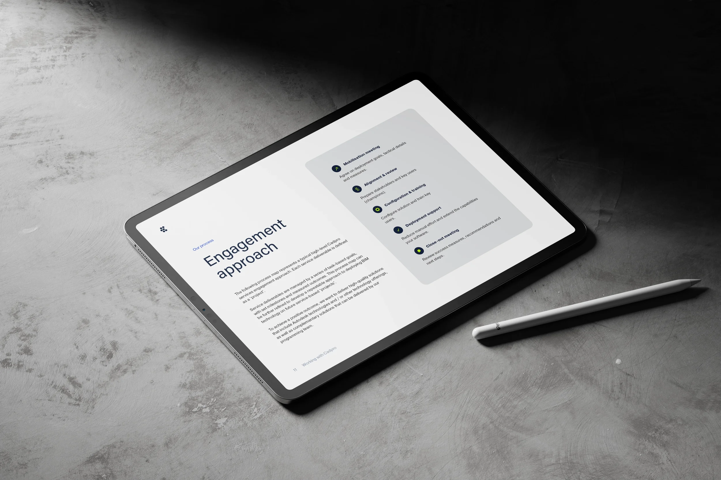 A tablet on a gray surface displaying a webpage titled "Engagement approach" with sections about a process, meeting, review, and support. A white pen is placed nearby.