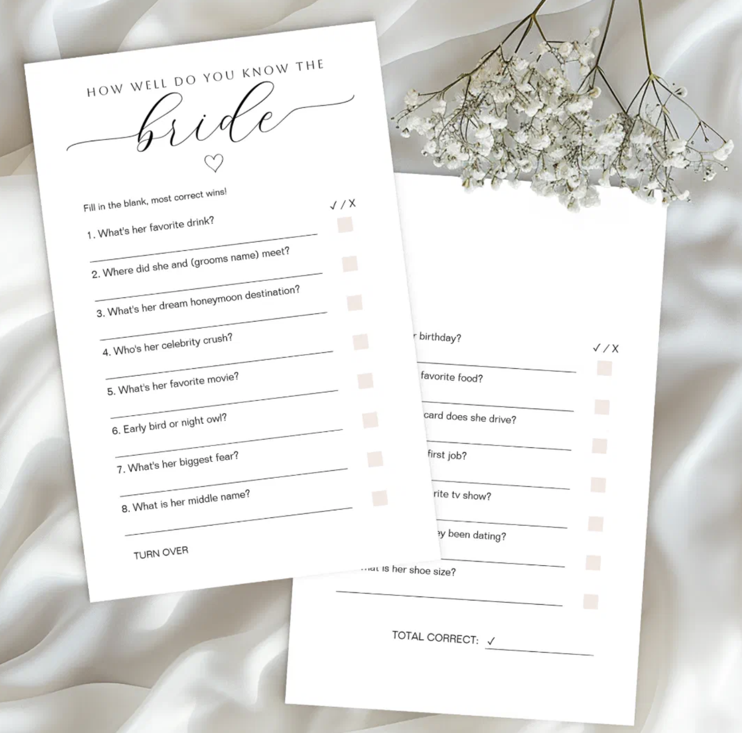 Elegant How Well Do You Know the Bride bridal shower game cards displayed on white satin fabric with baby's breath flowers. Minimalist printable bridal shower trivia game with blush accents and stylish script design.