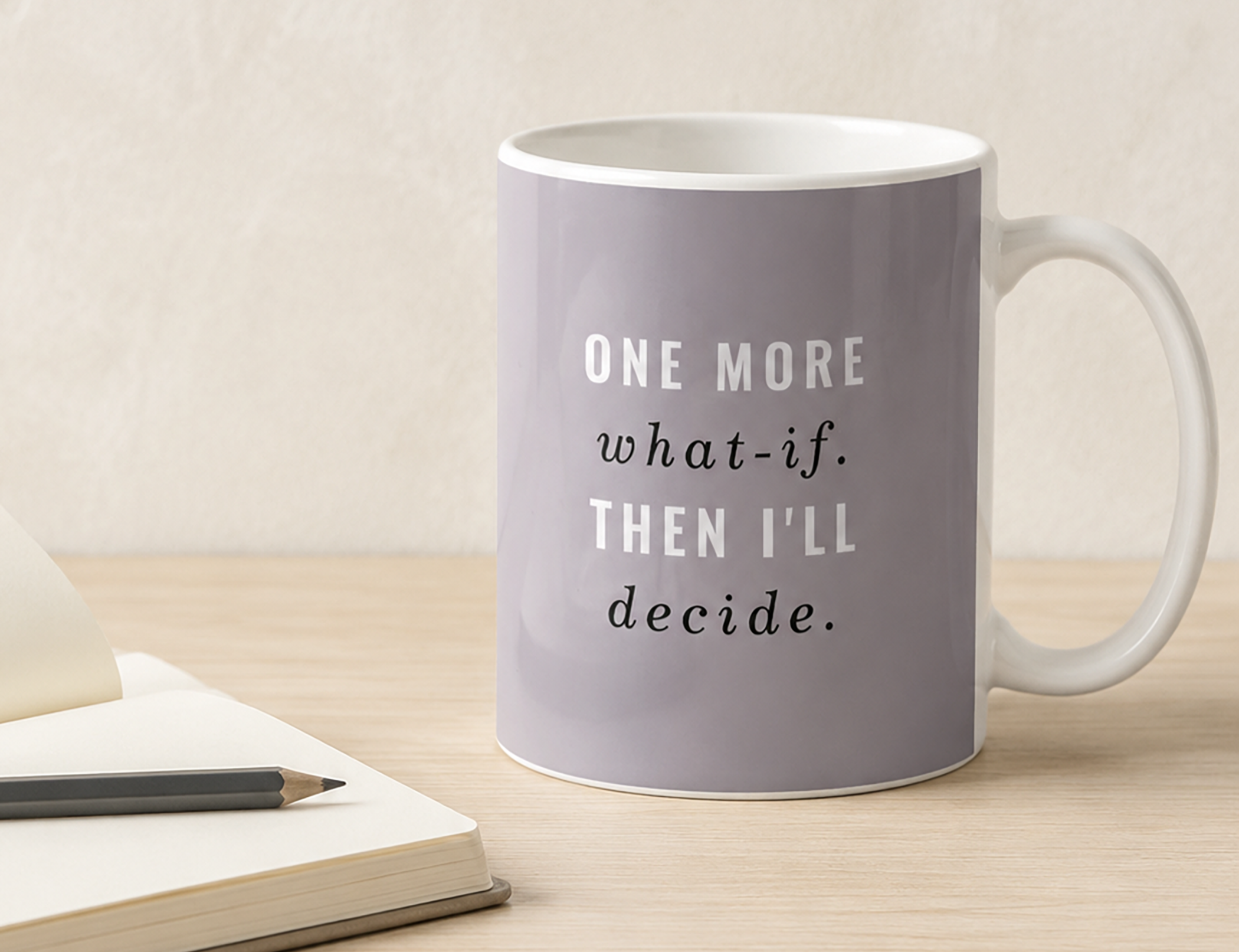 Lavender grey coffee mug reading “One More What-If. Then I’ll Decide.” beside books and a pencil on a warm neutral desk.