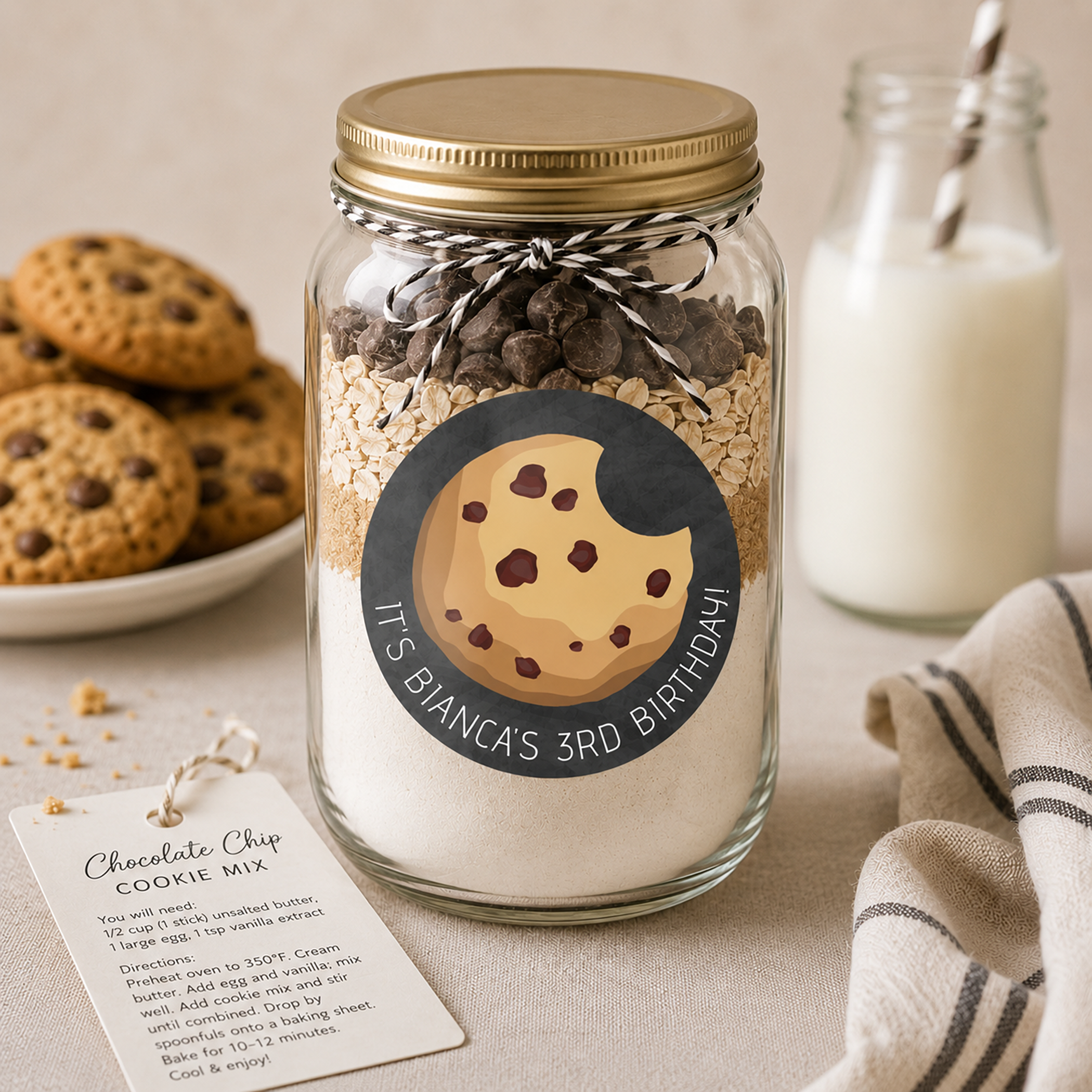 Glass cookie mix jar party favor with a personalized milk and cookies birthday sticker, styled with chocolate chip cookies, a milk bottle, and cozy neutral farmhouse decor in a warm bakery-inspired setting.
