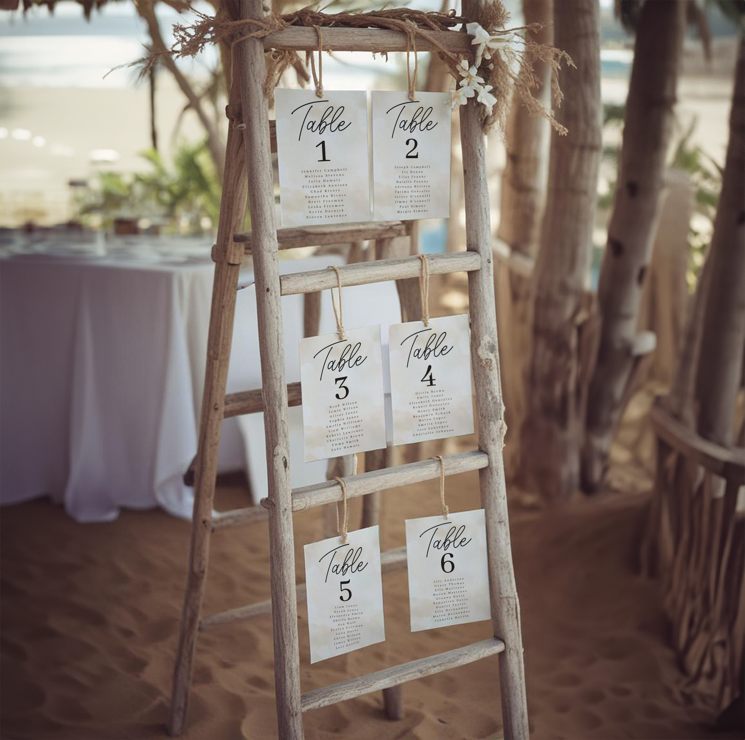 Watercolor beach wedding seating chart displayed at an outdoor coastal reception