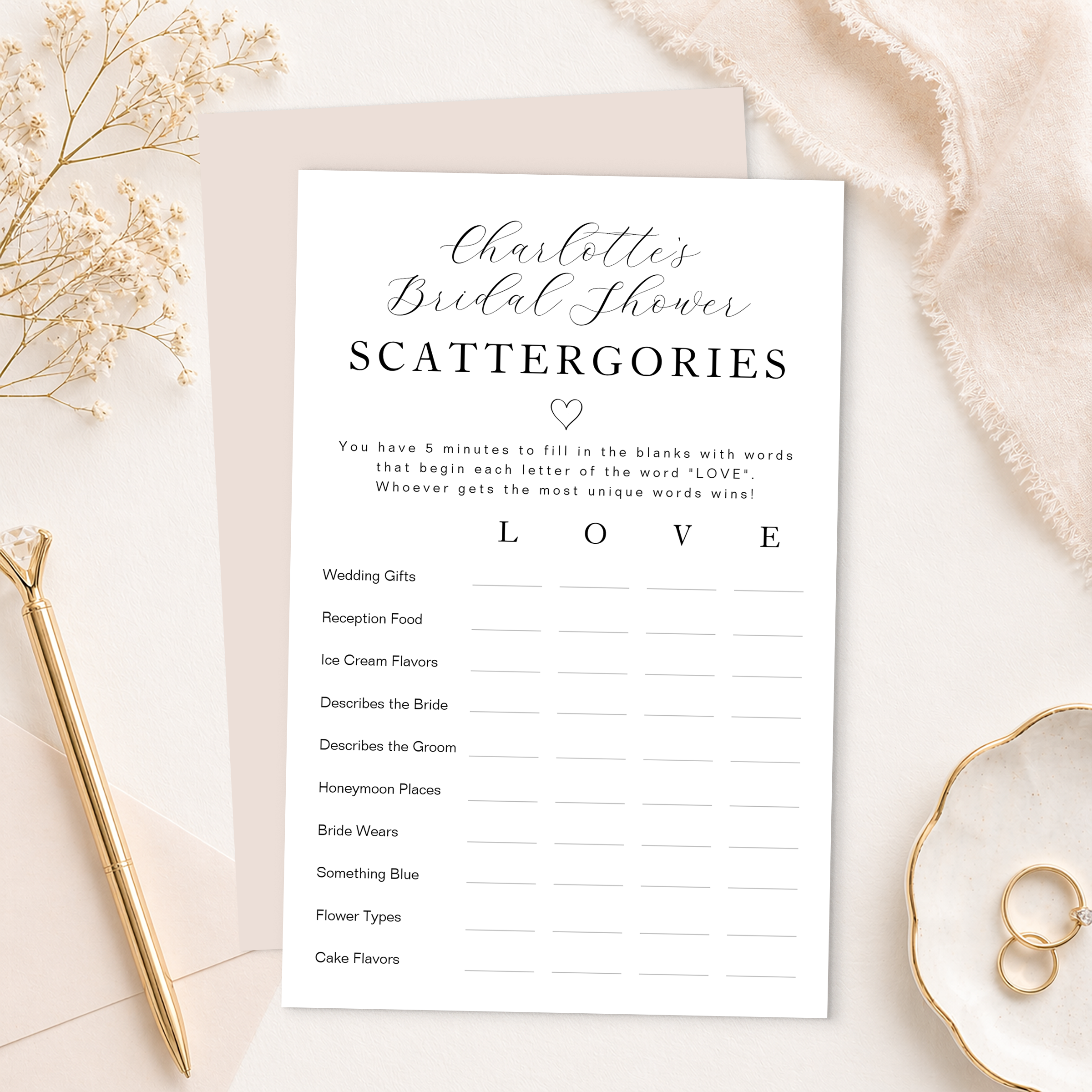Elegant bridal shower scattergories game card with blush backing sheet, gold pen, rings, envelope, and soft neutral styling. Printable bridal shower word game featuring categories and LOVE letter prompts for guests.