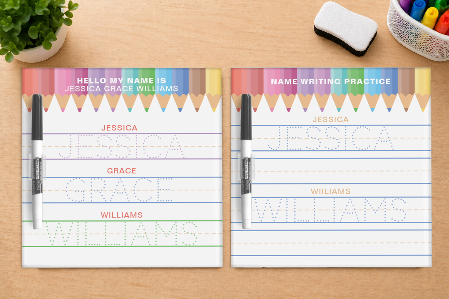 Two colorful square personalized dry erase name writing practice boards on a wooden desk with tracing lines, custom child names, marker pens, and classroom accessories.
