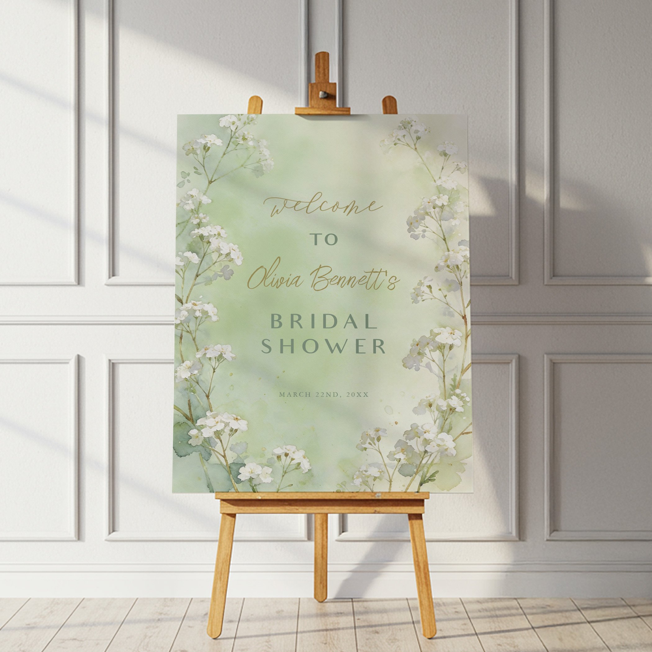 Sage green floral bridal shower welcome sign on an easel with delicate watercolor wildflowers in a romantic garden style.
