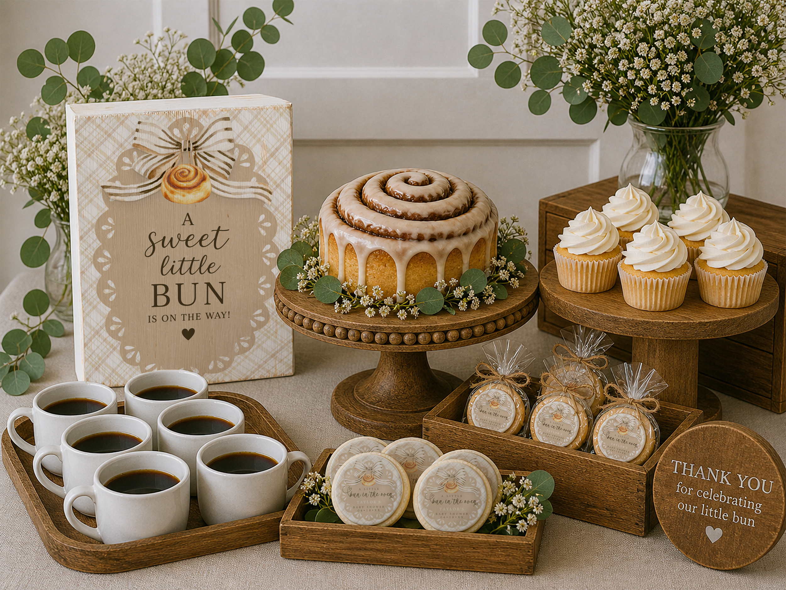 Neutral baby shower dessert table with wooden cake stands, trays, and a distressed wood sign, featuring cinnamon roll cake, cupcakes, coffee mugs, and decorated cookies with soft greenery and floral accents.