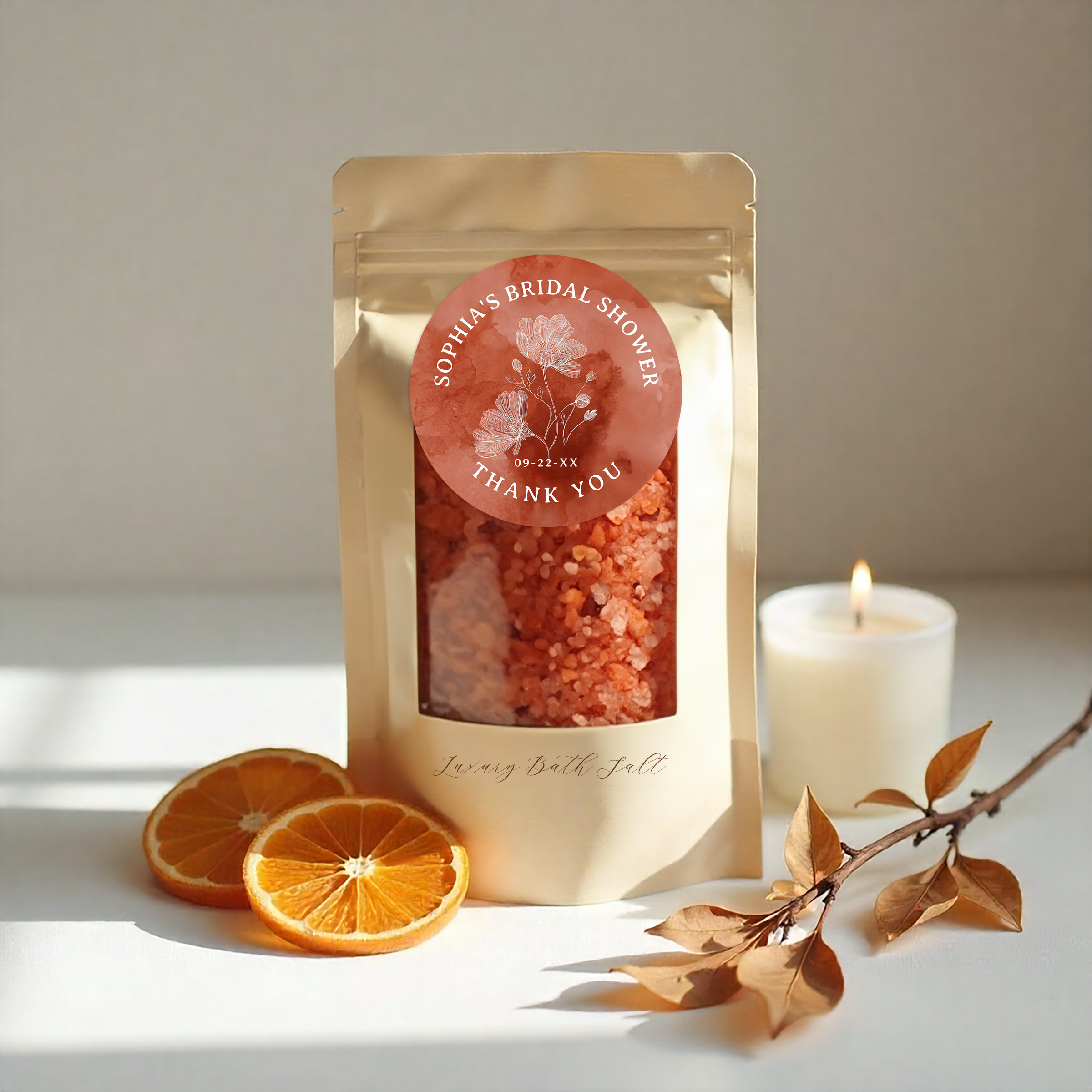 Terracotta bridal shower bath salt favor in a kraft stand-up pouch with personalized floral thank you sticker, styled with candlelight, dried oranges, and autumn leaves.