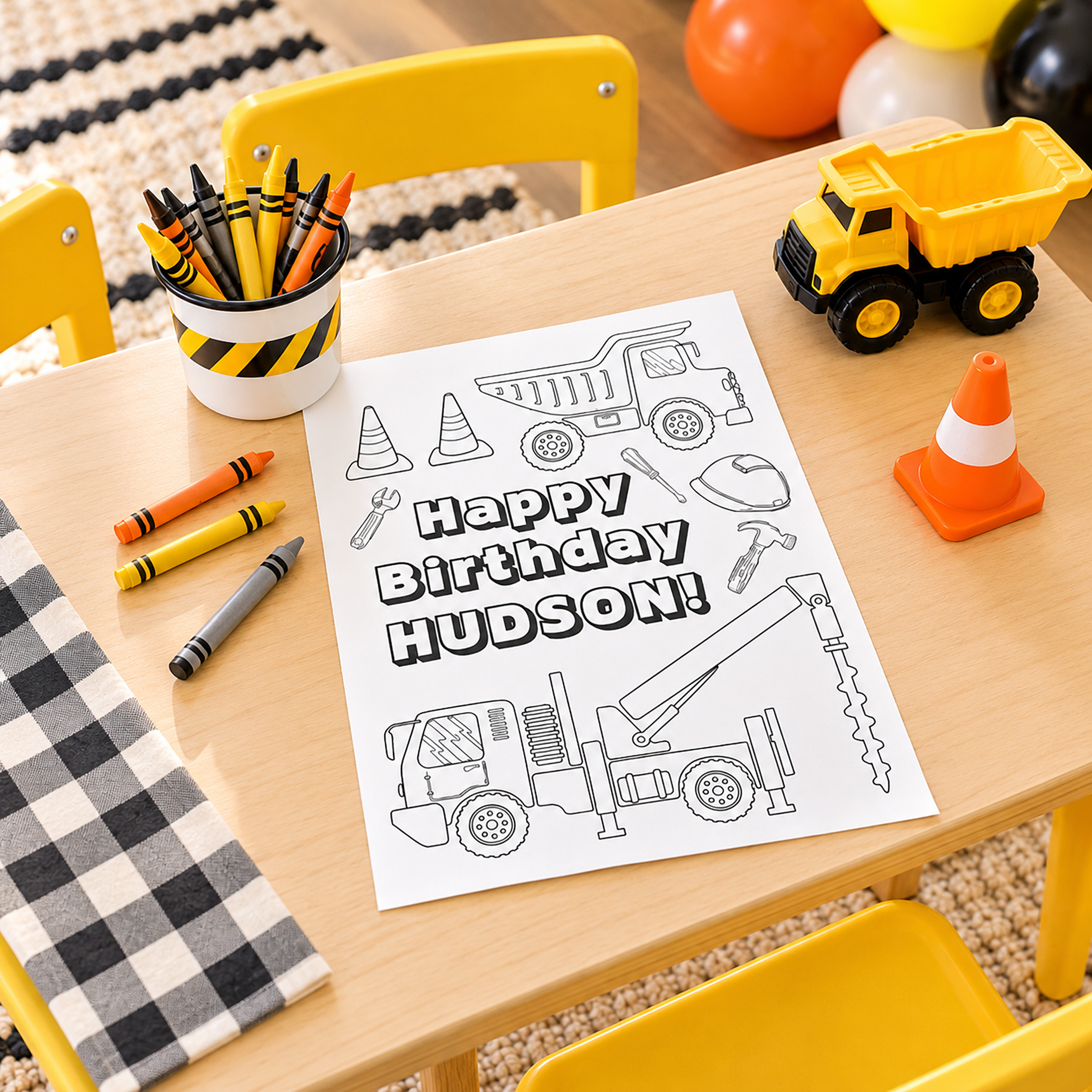 Construction birthday coloring station with personalized truck coloring page, yellow and orange crayons, toy dump truck, traffic cone, and child-size yellow chairs.