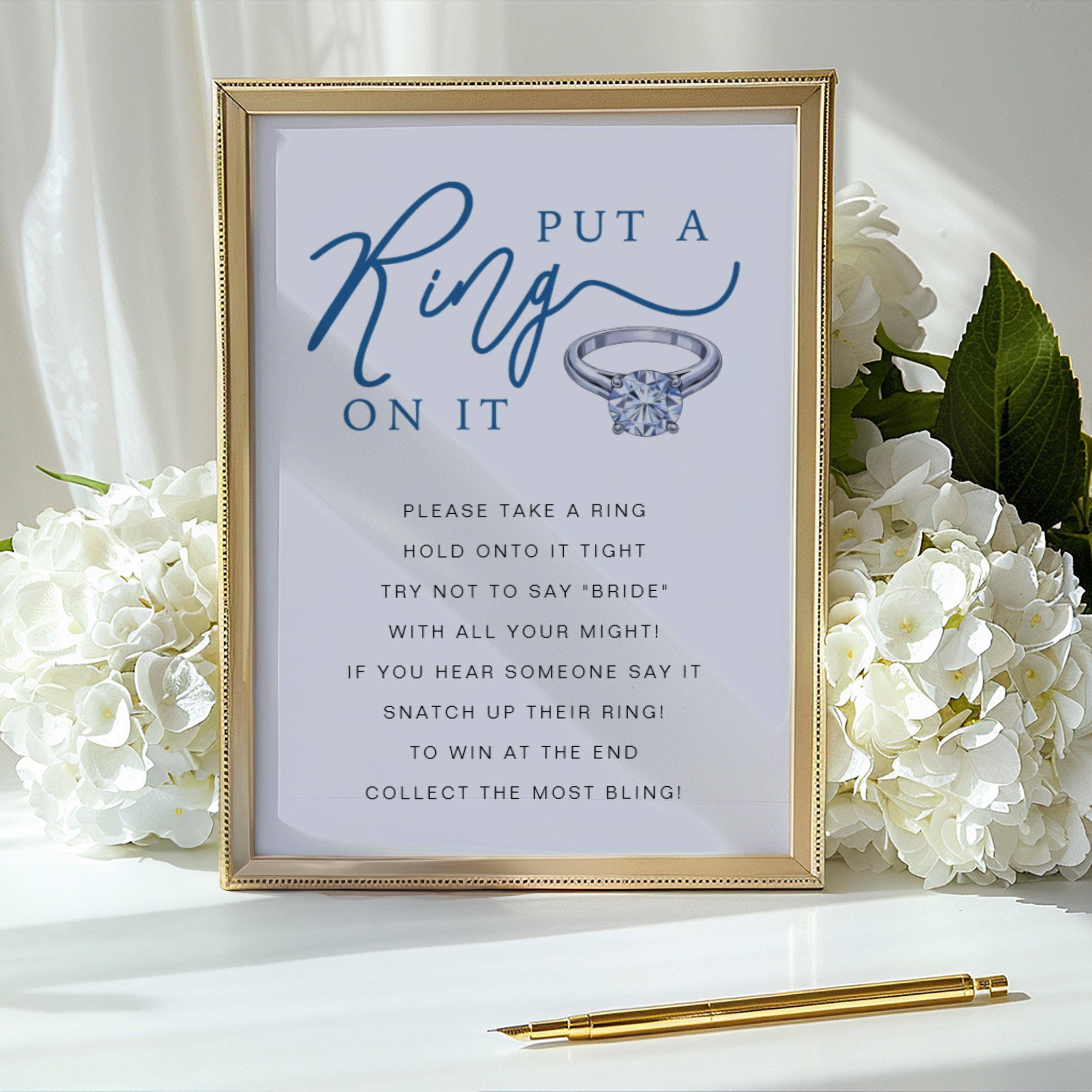 Bridal shower game sign in a gold frame reading “Put a Ring On It” with elegant blue script and engagement ring illustration.