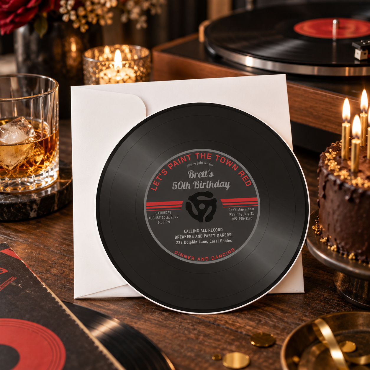 Vinyl record 50th birthday invitation styled with a turntable, candles, chocolate cake, glassware, and black, red, gold, and warm wood accents for an adult music-themed celebration.