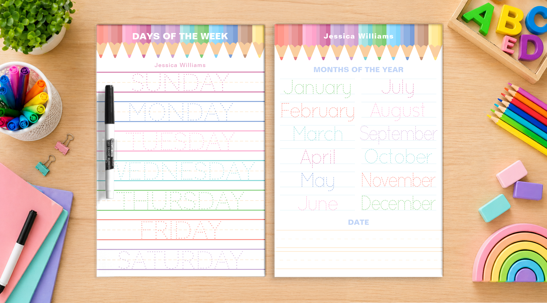Two personalized dry erase educational tracing boards on a wooden desk, one featuring days of the week and one featuring months of the year, surrounded by markers, pencils, pastel erasers, and rainbow toys.