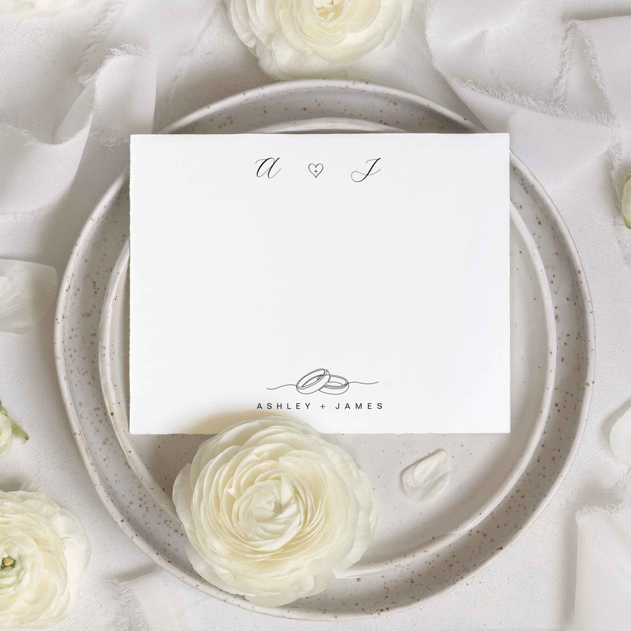 Minimalist couple monogram note card featuring two elegant script initials separated by a heart, with interlocking rings and names below on a soft neutral background.