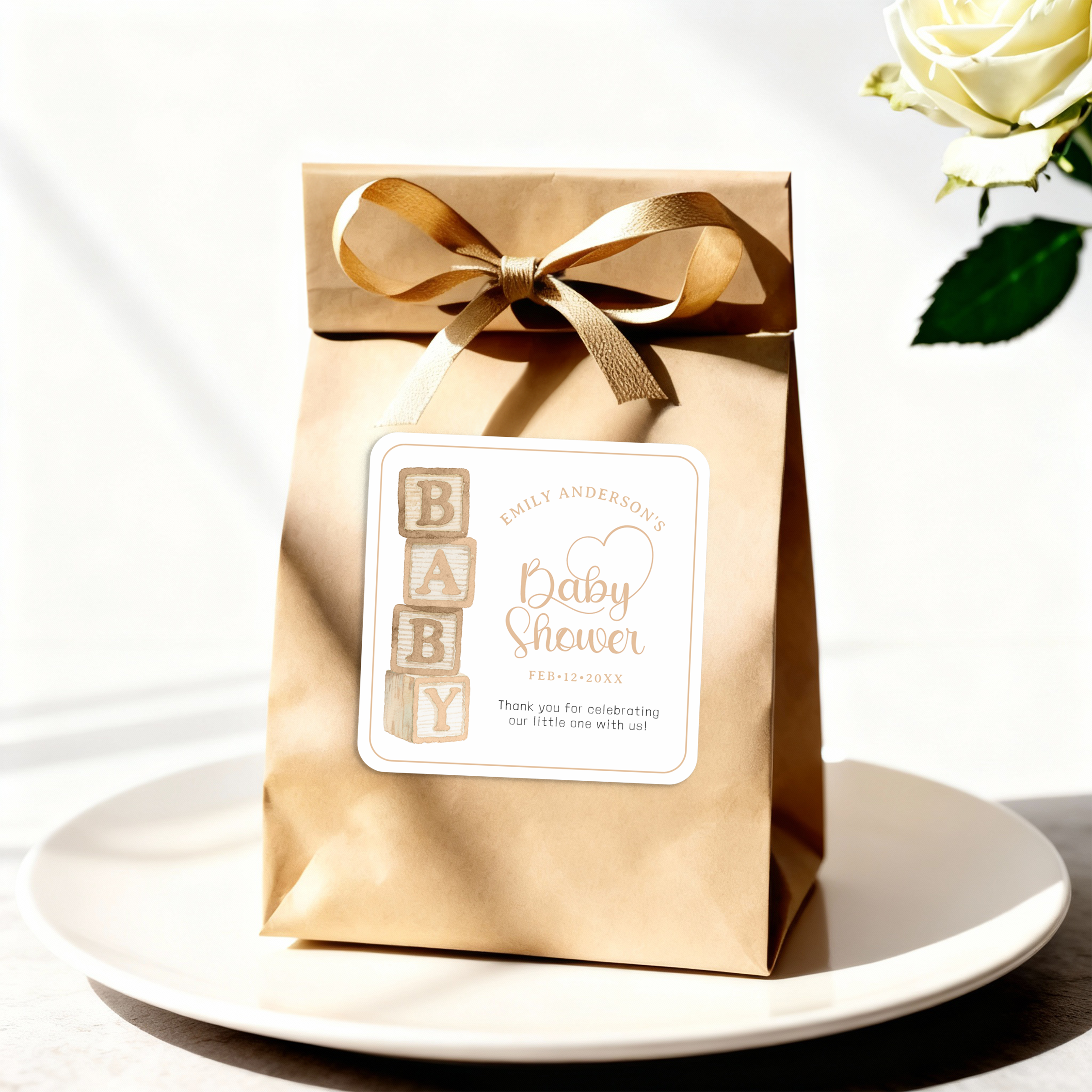 Taupe baby blocks baby shower favor sticker attached to a kraft gift bag with ribbon.