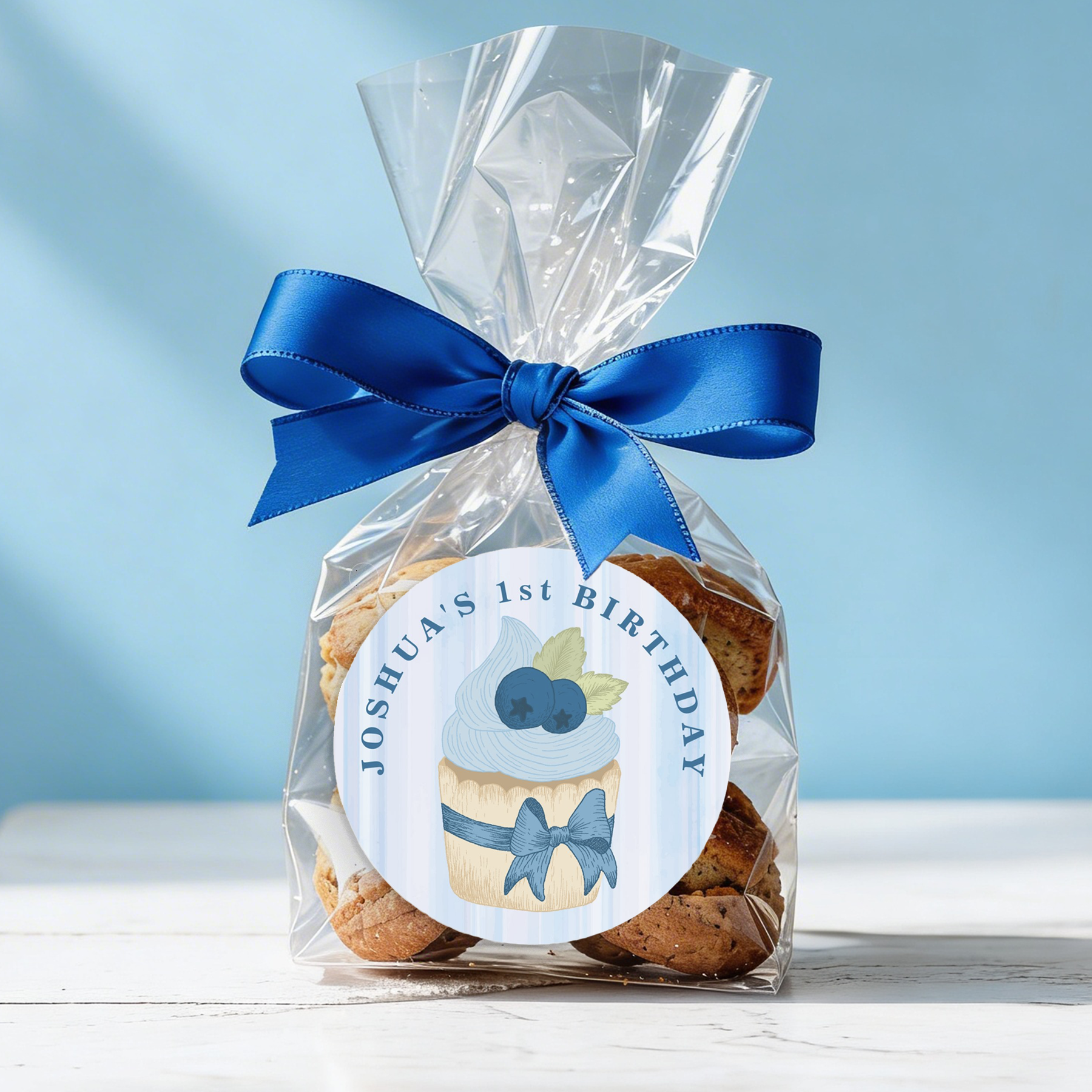 Blueberry cupcake birthday favor sticker on cookie bag tied with blue ribbon.