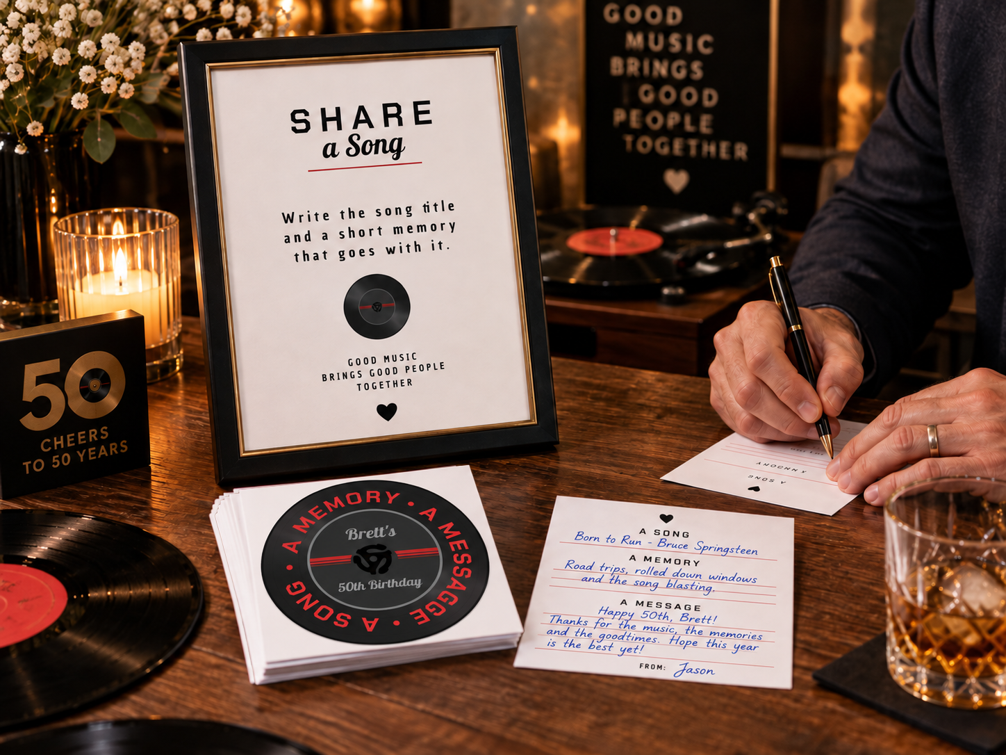 Vinyl-themed 50th birthday party scene showing “Share a Song” keepsake cards in use, with one card filled out by hand beside a record-style memory card on a wooden table with drinks and music-inspired decor.