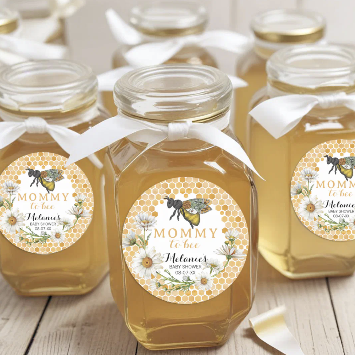 Honey jar baby shower favors with “Mommy to Bee” stickers featuring daisies, honeycomb pattern, and watercolor bee illustration