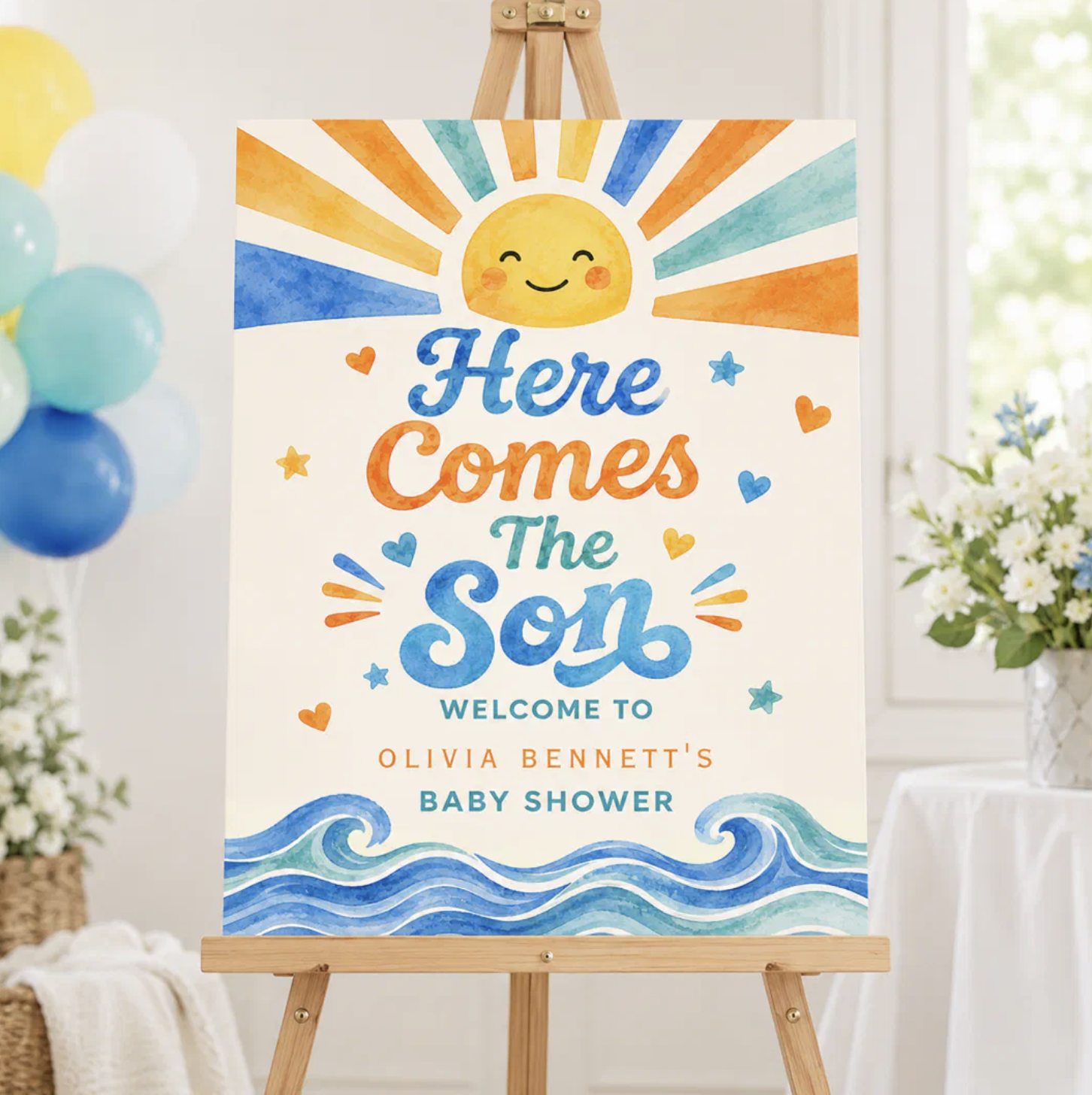 Personalized Here Comes the Son baby shower welcome sign displayed on a wooden easel featuring a smiling watercolor sun, blue ocean waves, and bright yellow, orange, and blue accents for a sunshine-themed baby shower entrance.