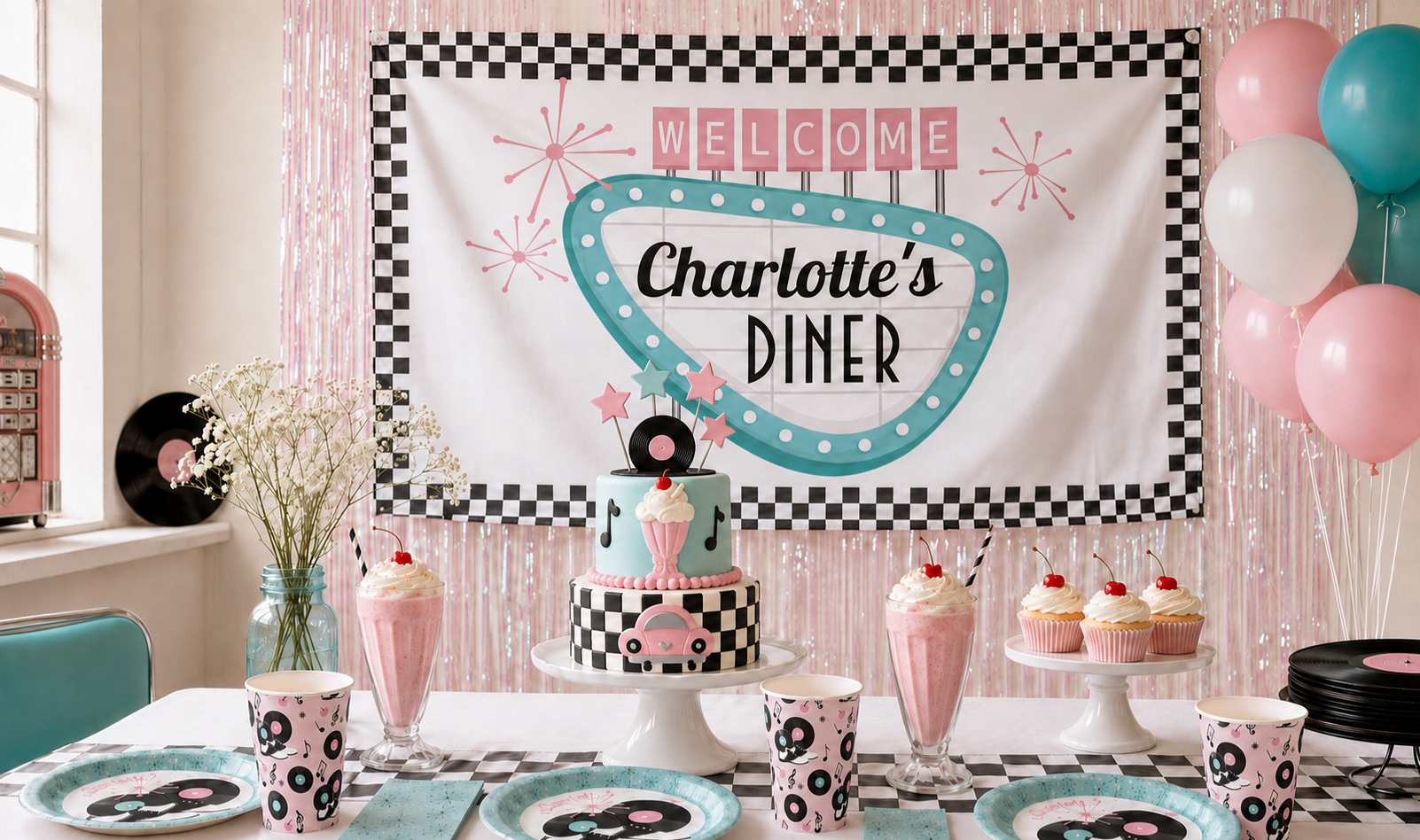 Pink and turquoise 1950s sock hop birthday table with a diner banner, retro cake, milkshakes, and record-themed tableware.