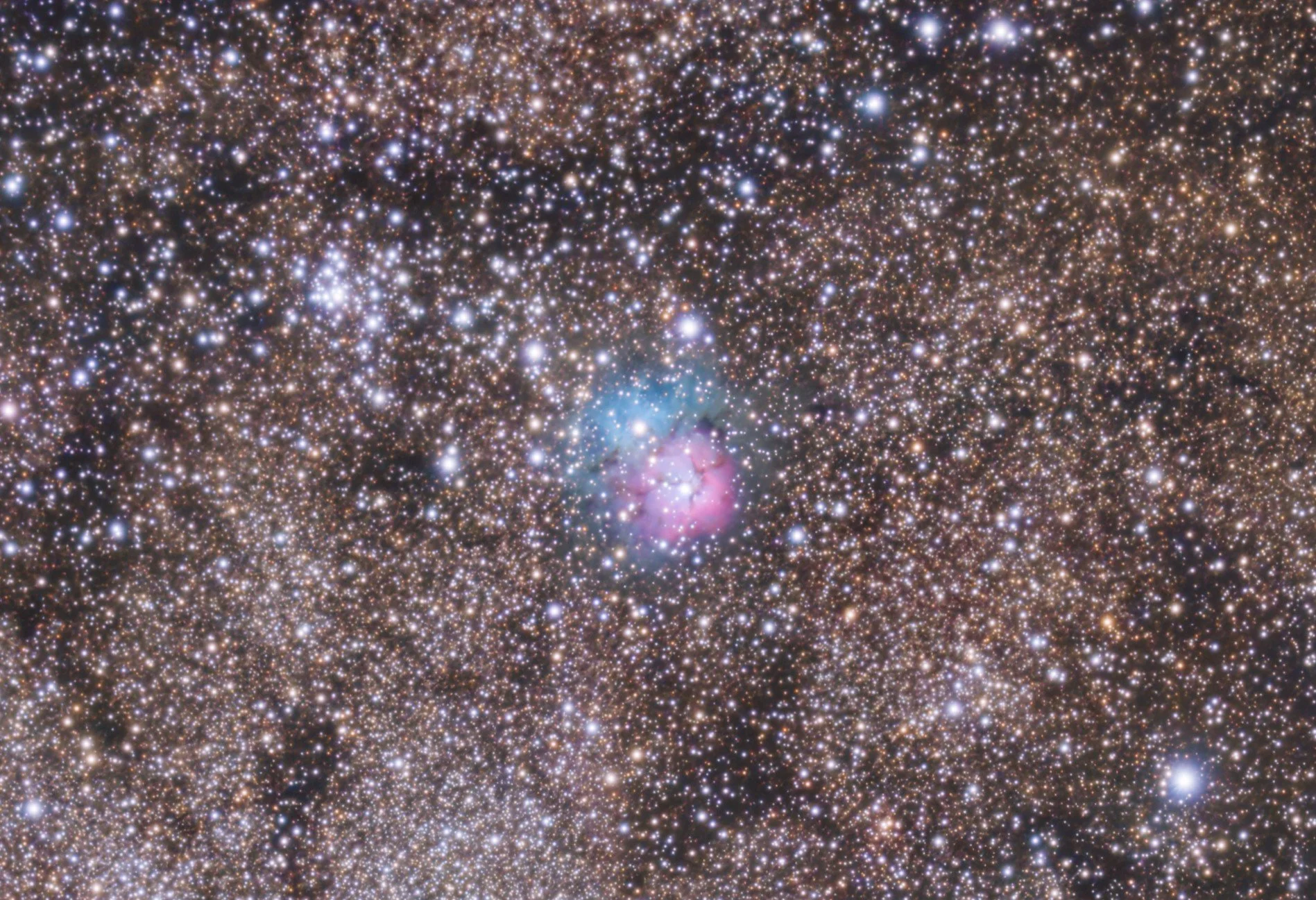 A dense star field in space with numerous stars, nebulae, and cosmic dust clouds.