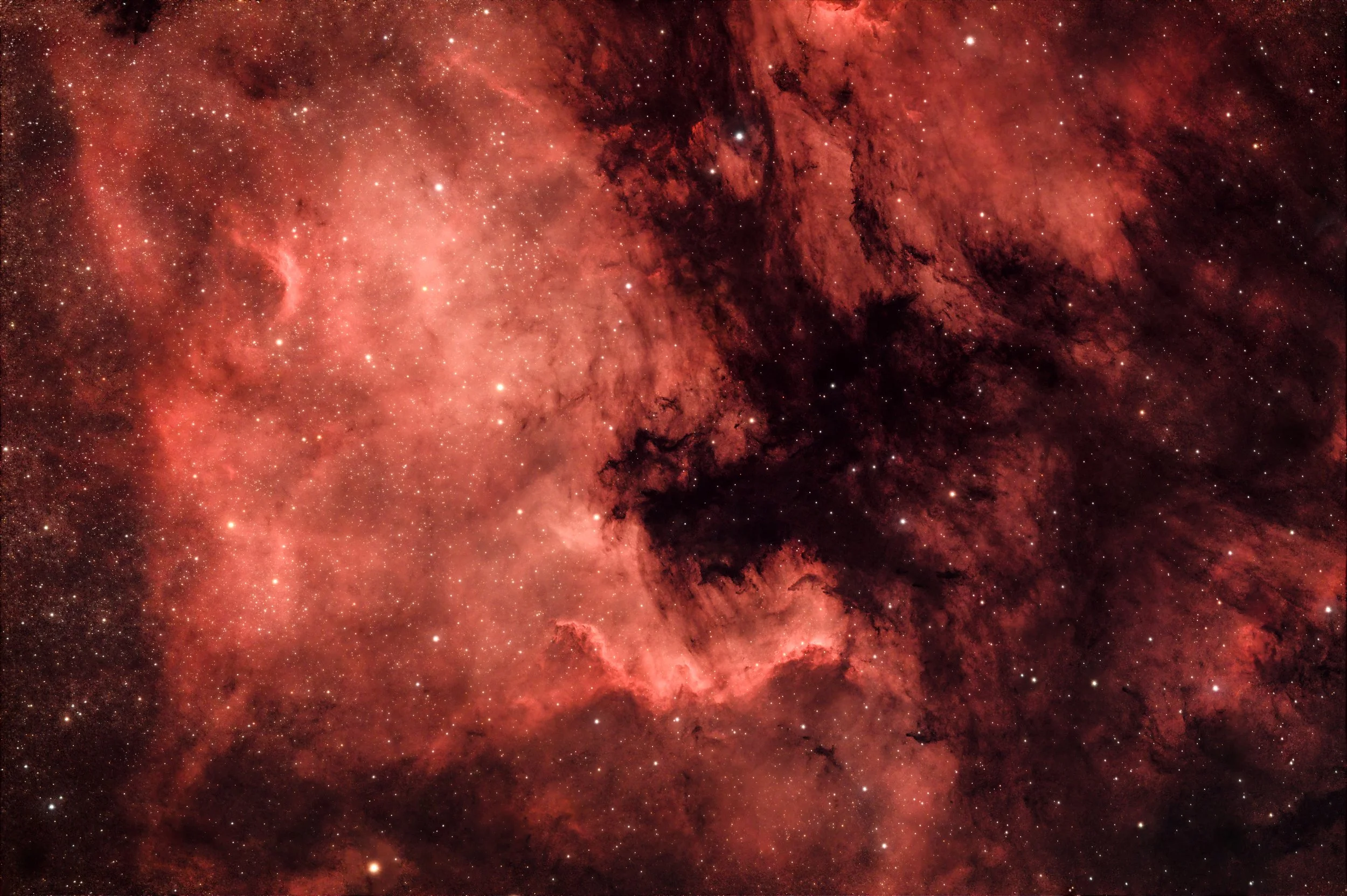 A vibrant image of the cosmos, featuring a nebula with red and orange hues, scattered with numerous bright stars.