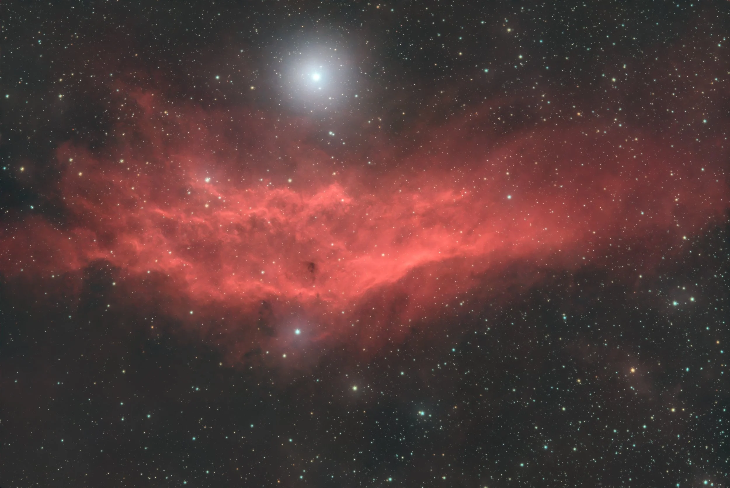 A view of space with numerous stars, a bright galaxy at the center, and a pinkish nebula.