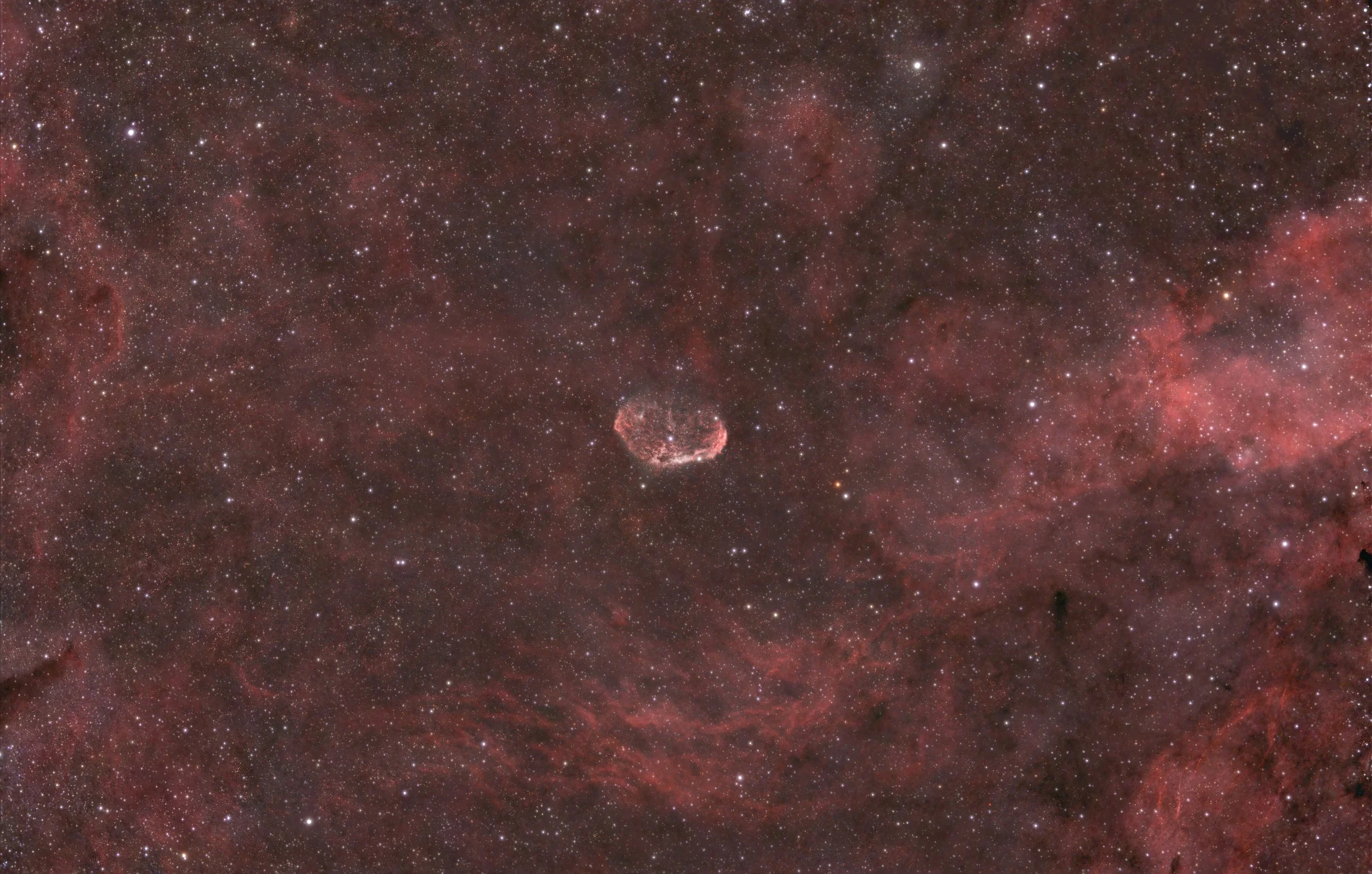 A vast view of space showcasing numerous stars, nebulae, and cosmic dust with a dust cloud and a bright nebula at the bottom center.