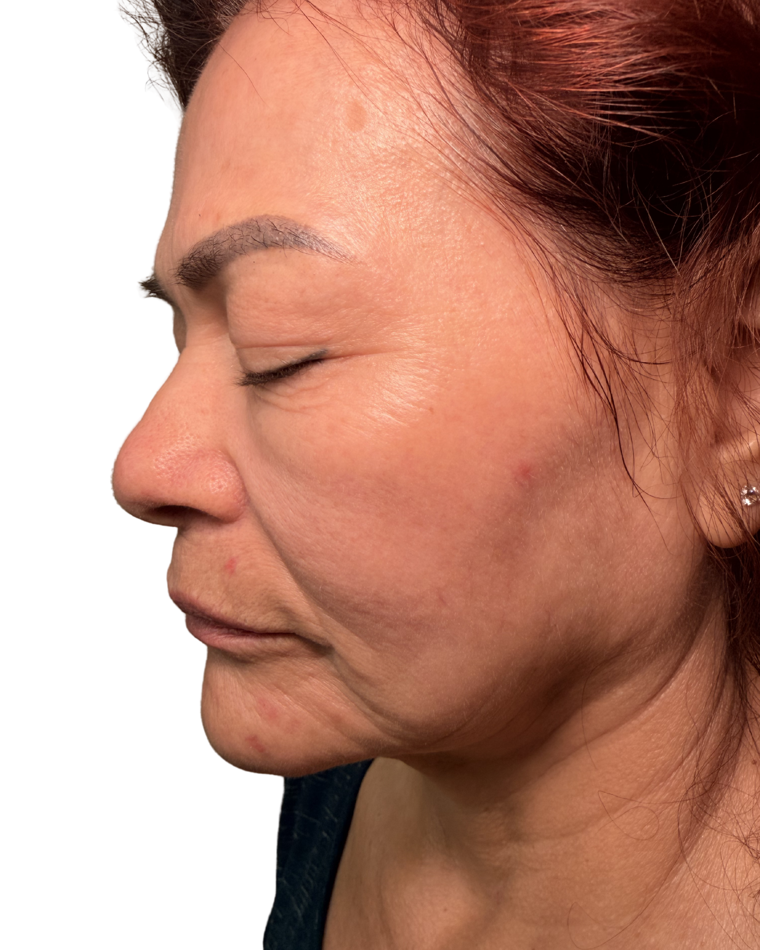 Close-up of a woman's face with closed eyes, red hair, and smooth skin.