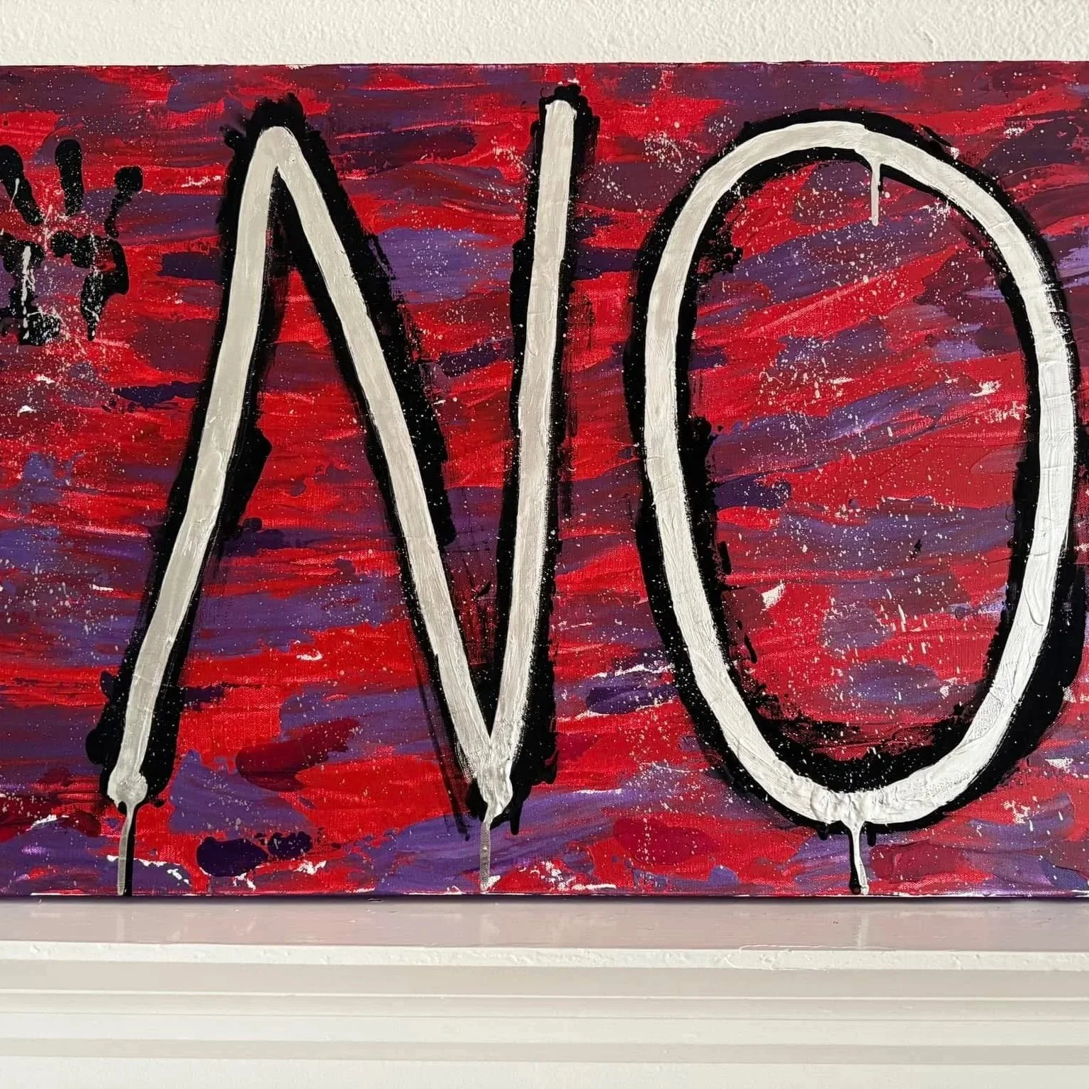 Close-up of a colorful abstract painting with bold black and white letters spelling 'LOVE' on a red, purple, and blue background.