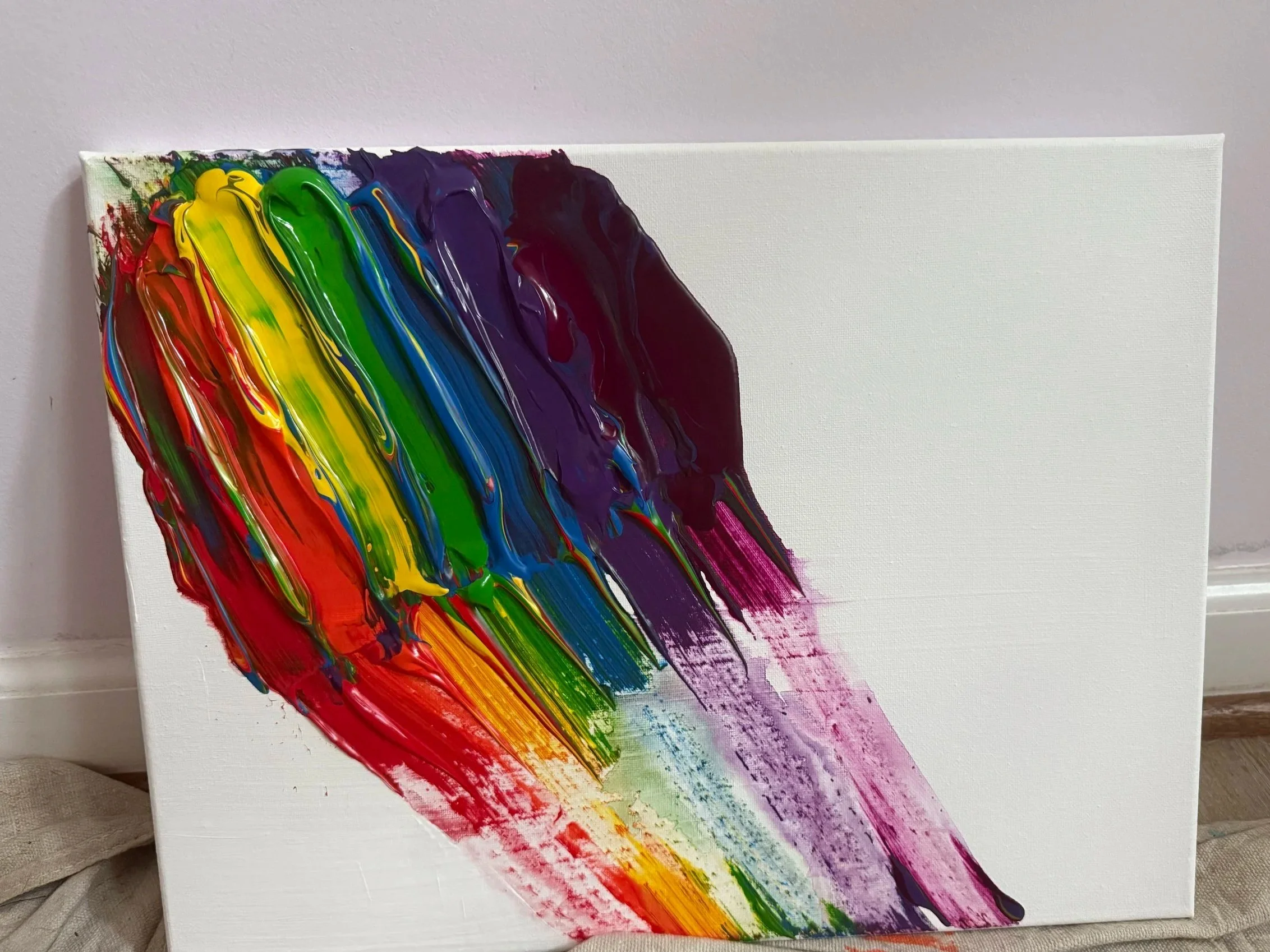 A blank white canvas with vibrant rainbow-colored paint streaks on the left side, created with thick brushstrokes in red, orange, yellow, green, blue, purple, and pink.