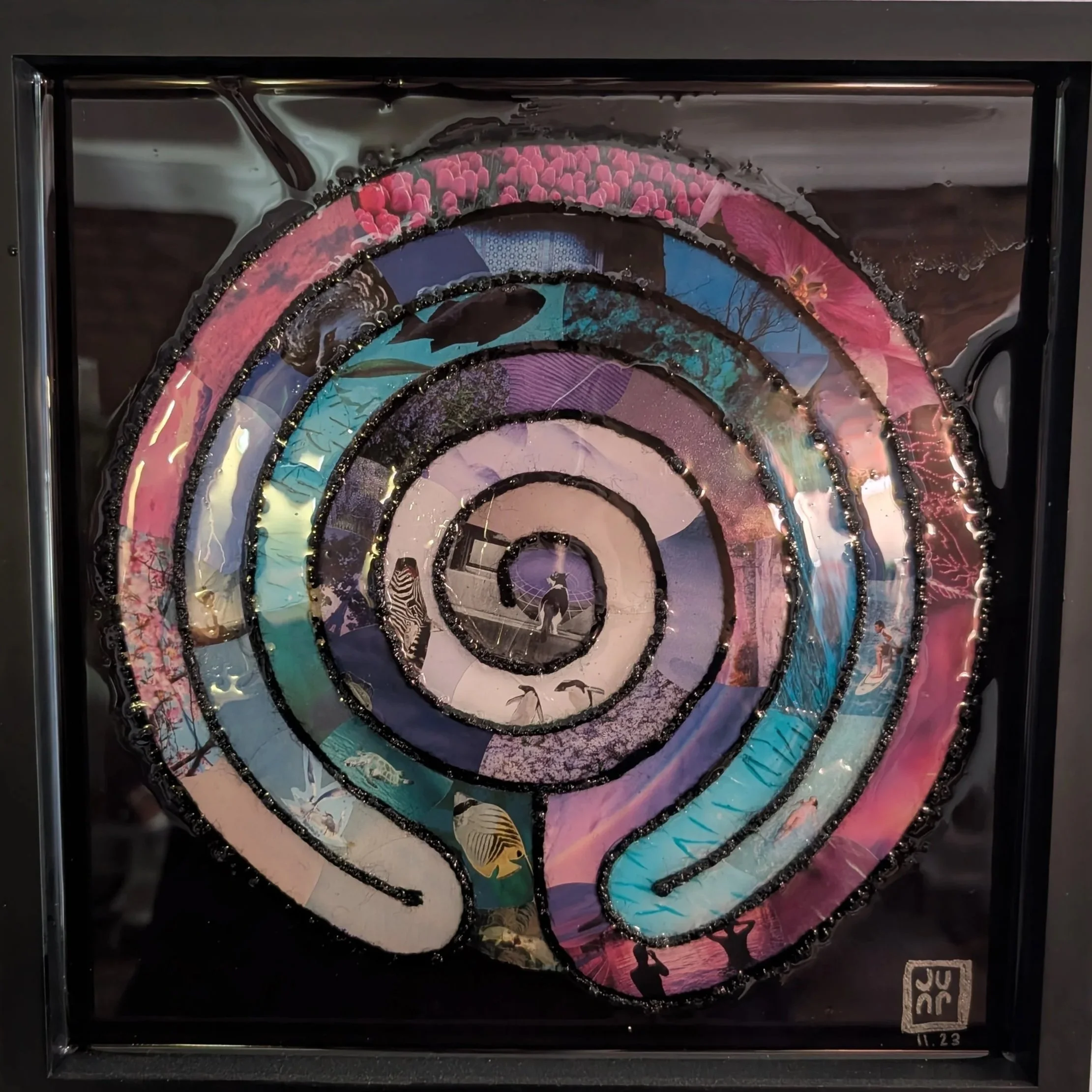 A spiral-shaped labyrinth collage artwork with colorful scenes and silhouettes of people, animals, and nature, arranged in concentric circles.