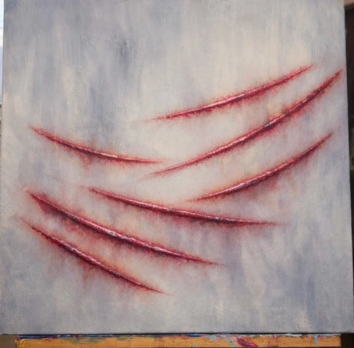 An artwork of a human chest with multiple red, raw-looking scratches arranged in a pattern.