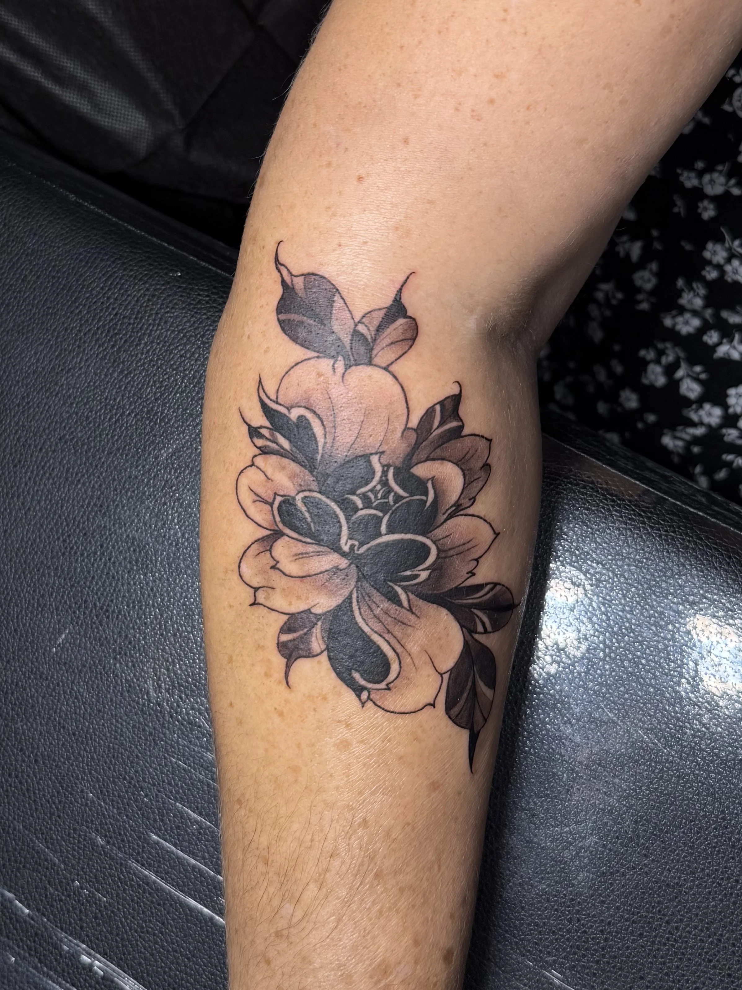 Black and gray floral tattoo with two butterflies on a person's forearm.