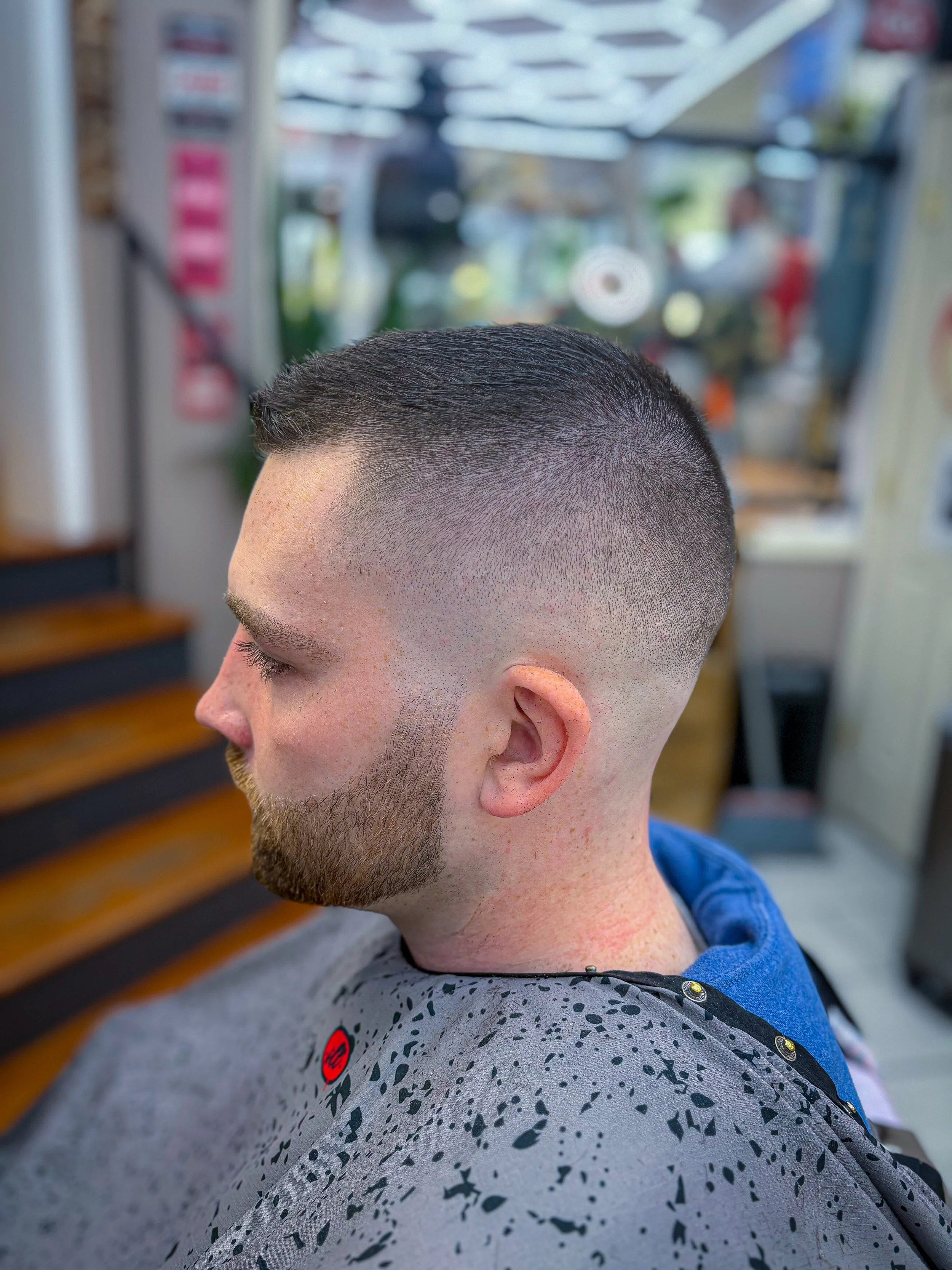 Man with a fresh fade haircut and beard sitting in barber shop.