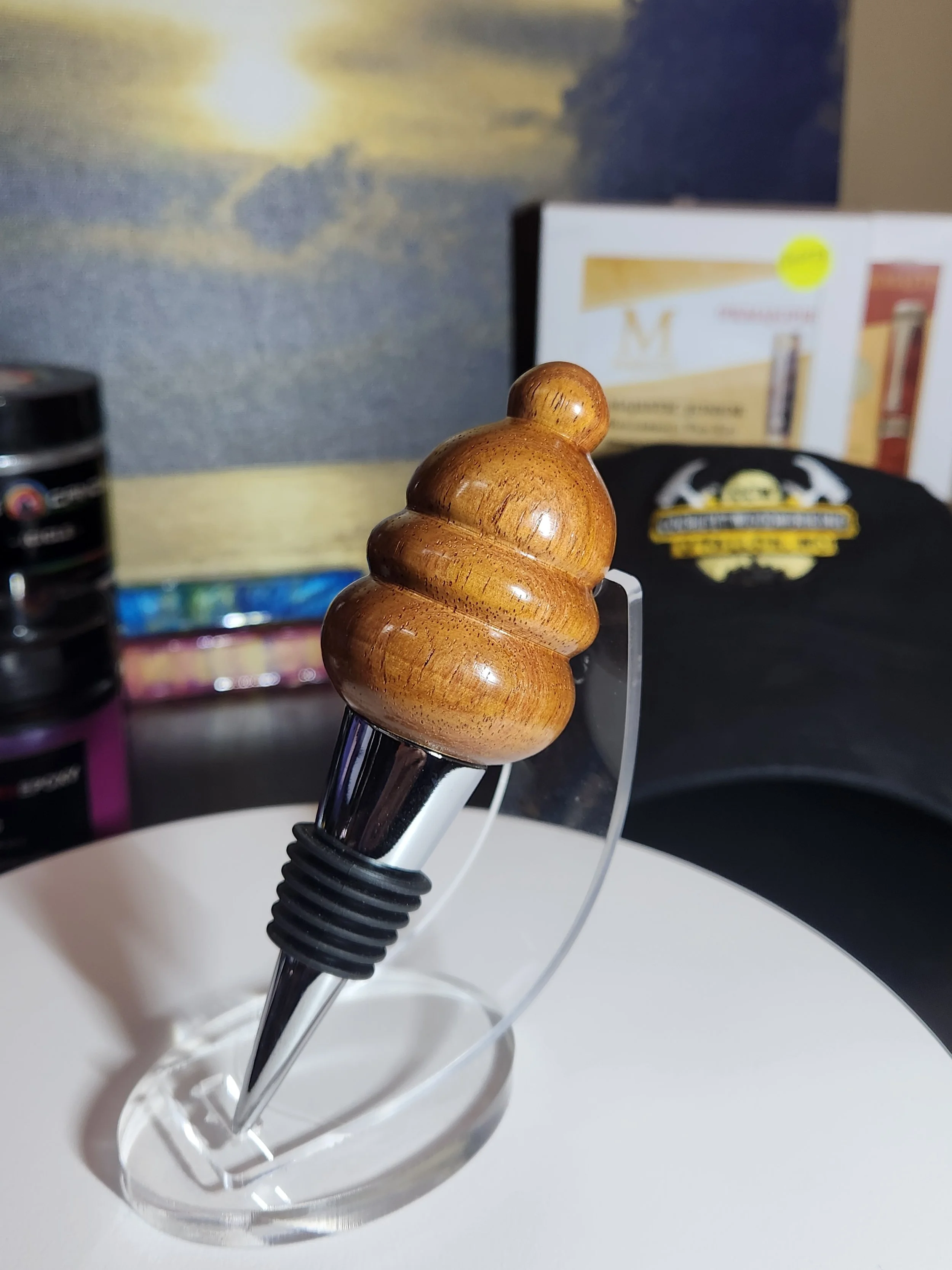A pen with a wooden top resembling a Swiffer handle, placed in a clear ink stand on a white surface.