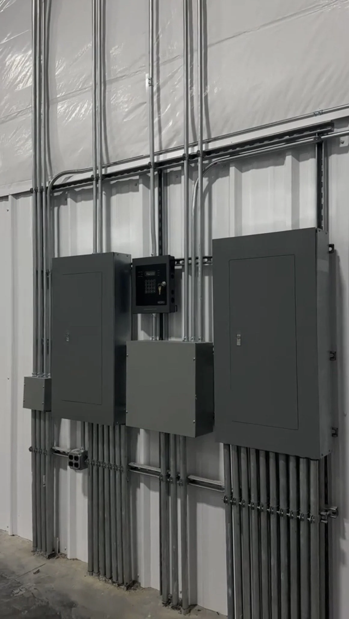 Interior view of electrical wiring and electrical panels mounted on a wall in a building.