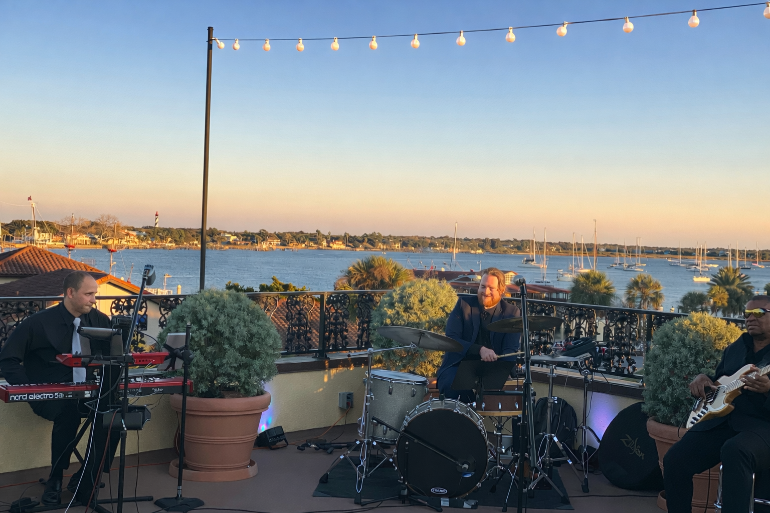 The Beach City Band performing live at a Jacksonville wedding and corporate event with keyboard, drums, and bass at an upscale rooftop venue.