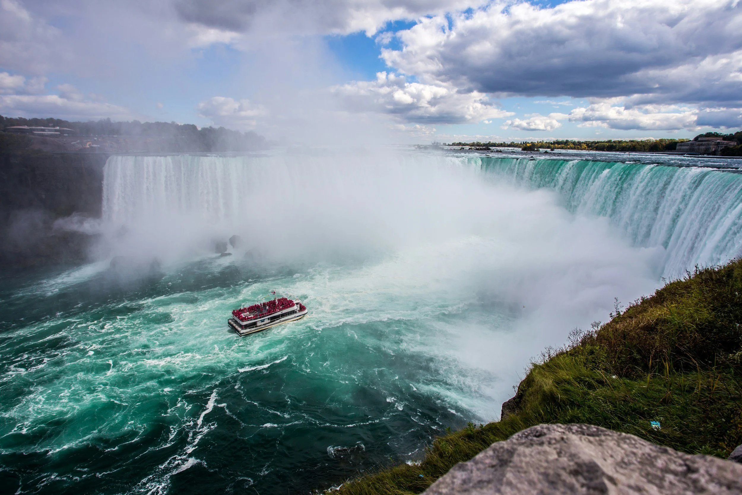 Niagara Falls with a boat near the waterfall and a cloudy sky.