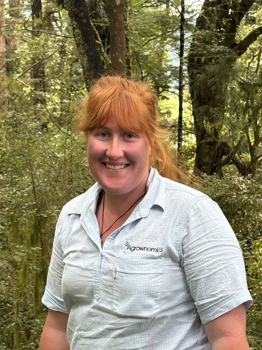 Renee Wood Agrownomics Soil Consultant, smiling in a forested area, wearing a light gray shirt.