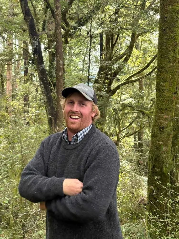 Cameron Campbell Agrownomics Soil Consultant ,standing in a wooded forest with trees and greenery.