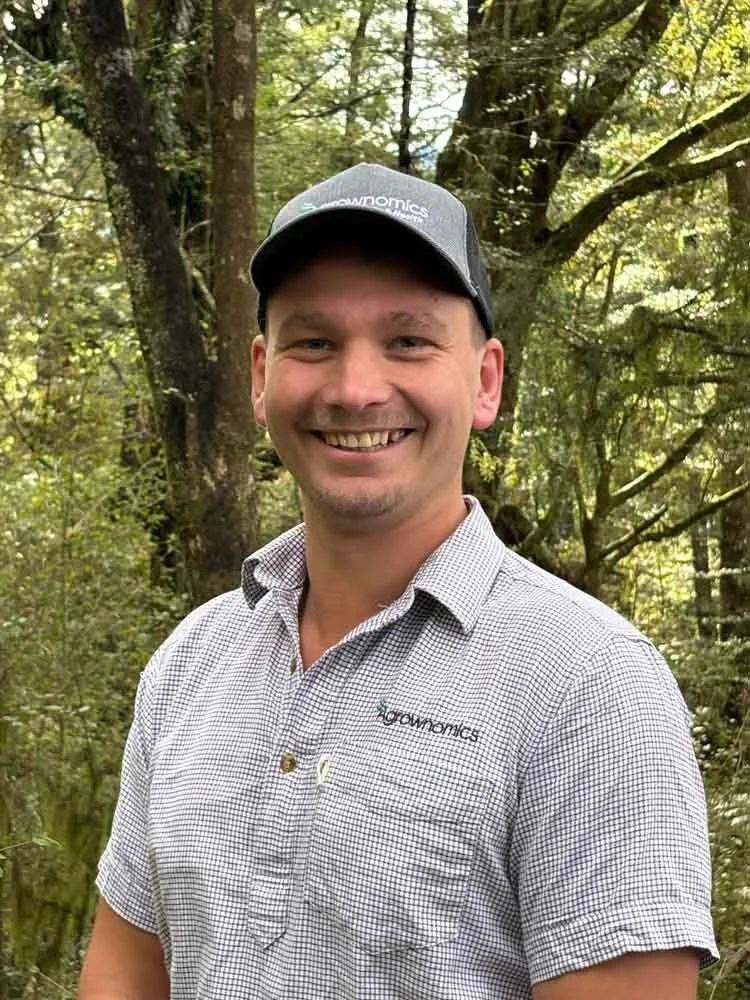 Findal Proebst Agrownomics Soil Consultant, standing outdoors in a forested area with green trees.