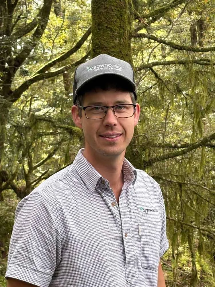 Matt Hight Agrownomics Senior Soil Consultant – Dairy & Pastoral, standing in a forest with green trees and branches in the background.