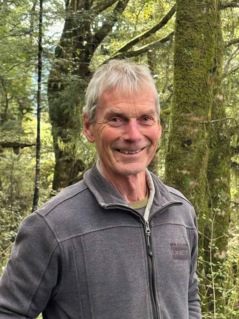 Lachy Hynd Agrownomics Soil Consultant – Viticulture & Horticulture, outdoors in a forest with green trees and moss-covered trunks.