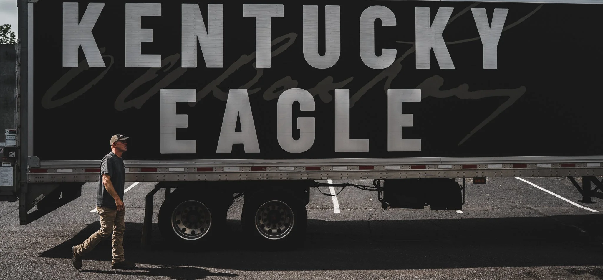 A man walking in front of a large black semi-truck trailer with 