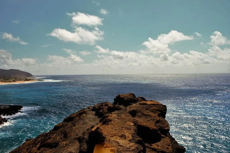 View of ocean and rocky coastline under partly cloudy sky
