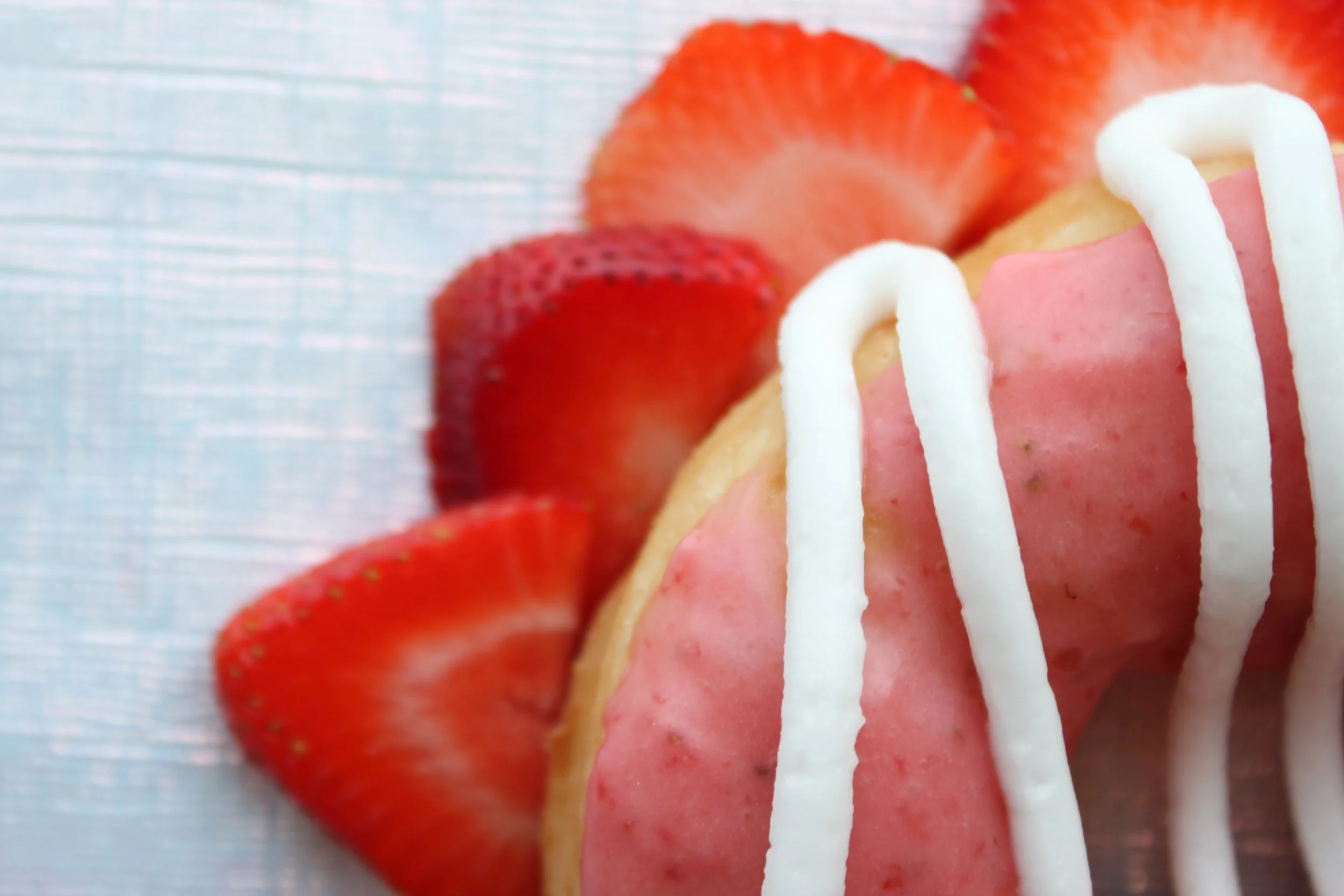 Close-up of a strawberry shortcake with sliced strawberries, pink icing, and white icing drizzle.