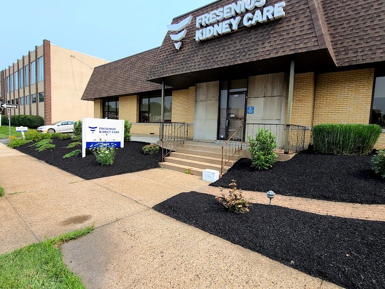 Building with a sign that reads 'Fresenius Kidney Care,' surrounded by a well-maintained garden and a sidewalk.